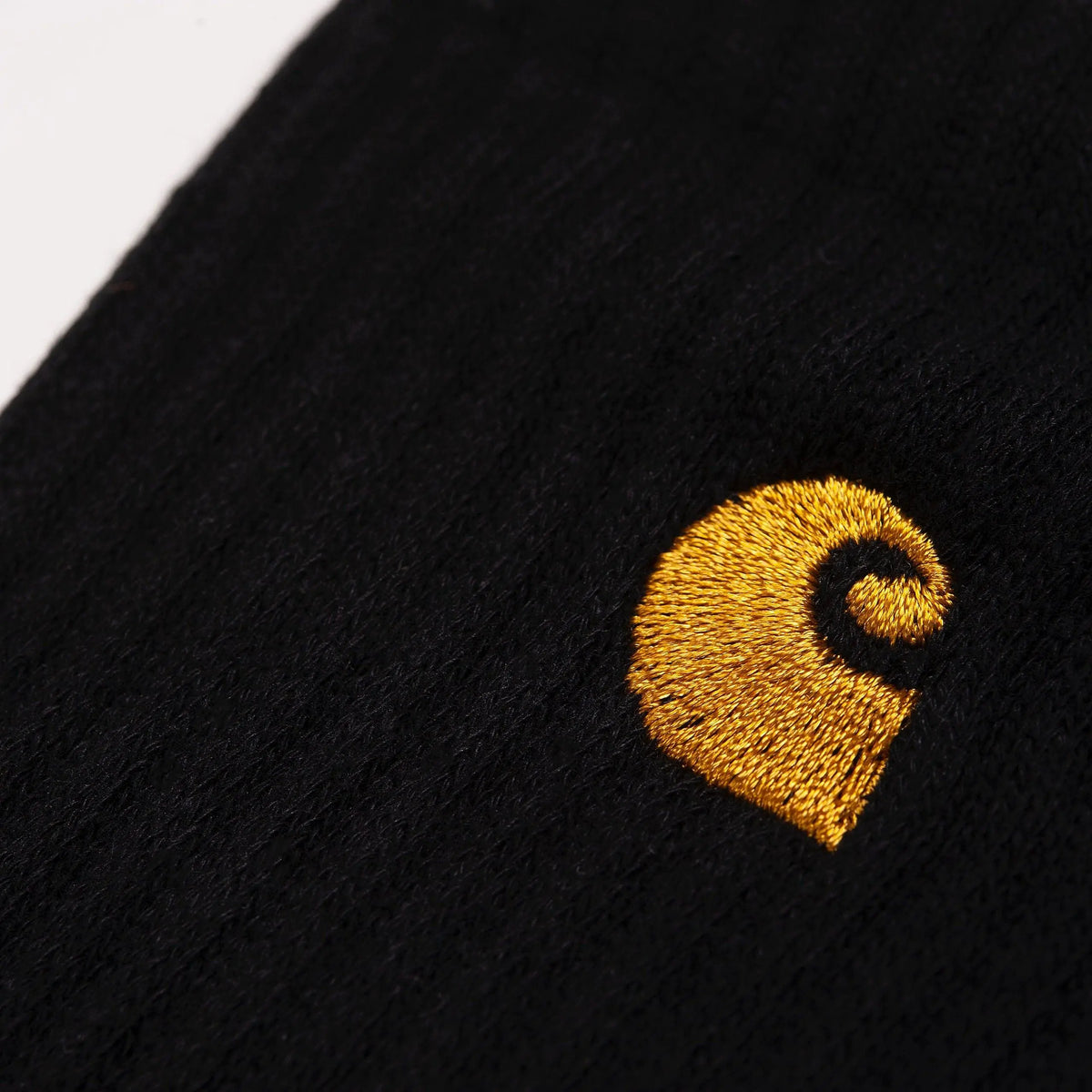 Détail macro : logo C brodé fil doré ressortant sur la maille noire côtelée de la tige d'une chaussette Chase