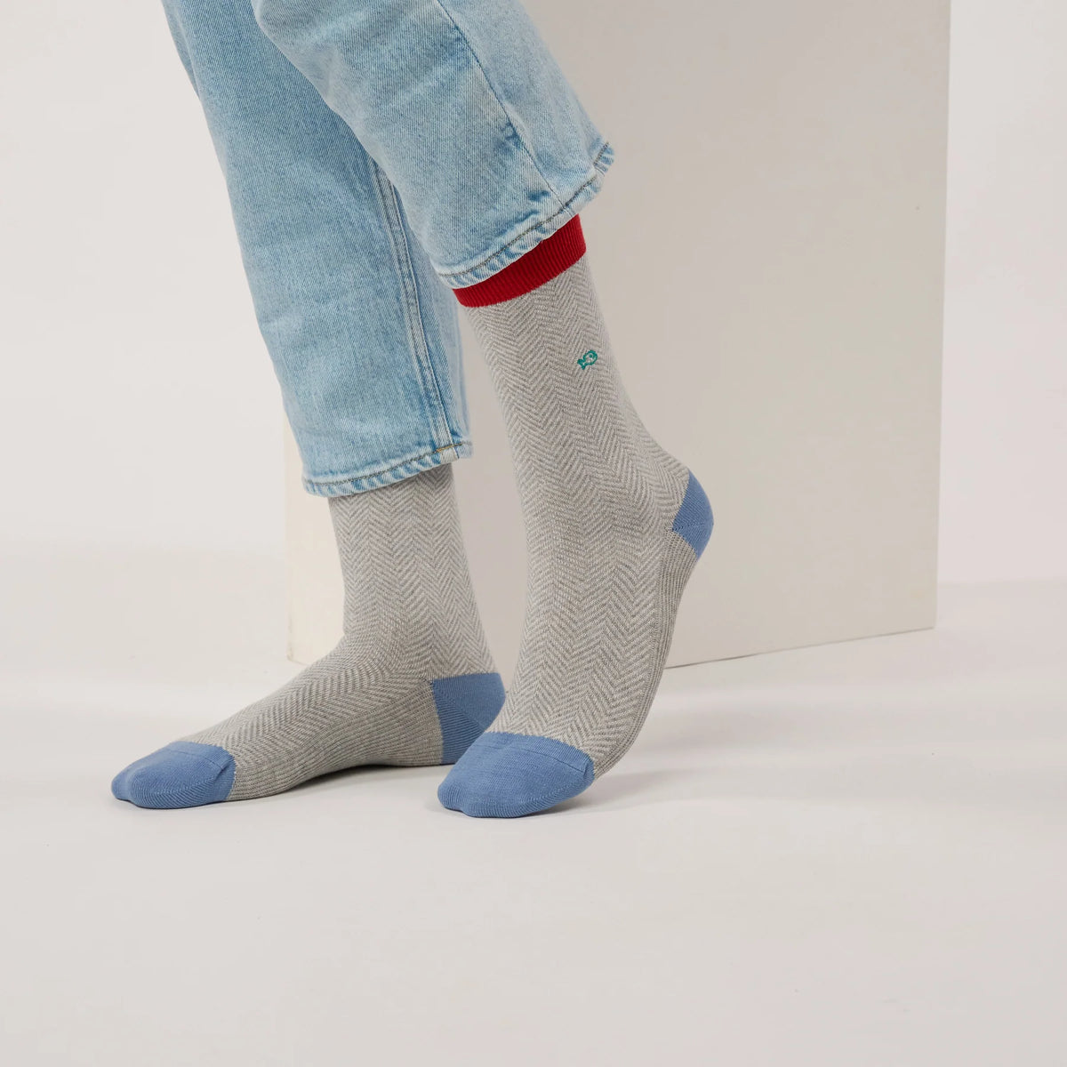 Chaussettes à chevrons gris cendré portées sous un jean clair retroussé, bord-côte rouge et pointes bleu ciel