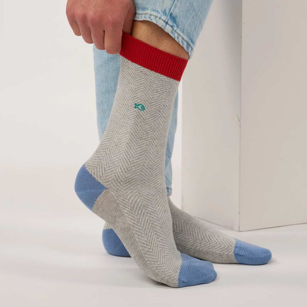 Chaussette à chevrons gris clair remontée sur la jambe, bord-côte rouge et petit poisson brodé turquoise