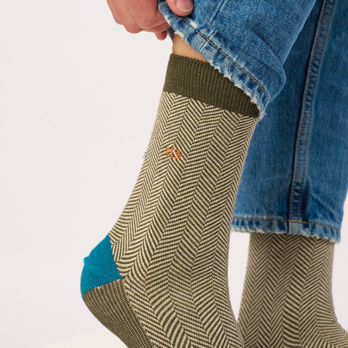Chaussette à chevrons kaki et écru tirée sur la cheville, bord-côte kaki et petit poisson brodé orange