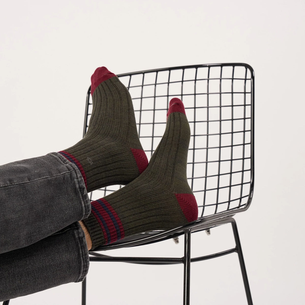 Chaussettes McGill BillyBelt portées pieds sur une chaise, maille côtelée kaki, talon et pointe bordeaux