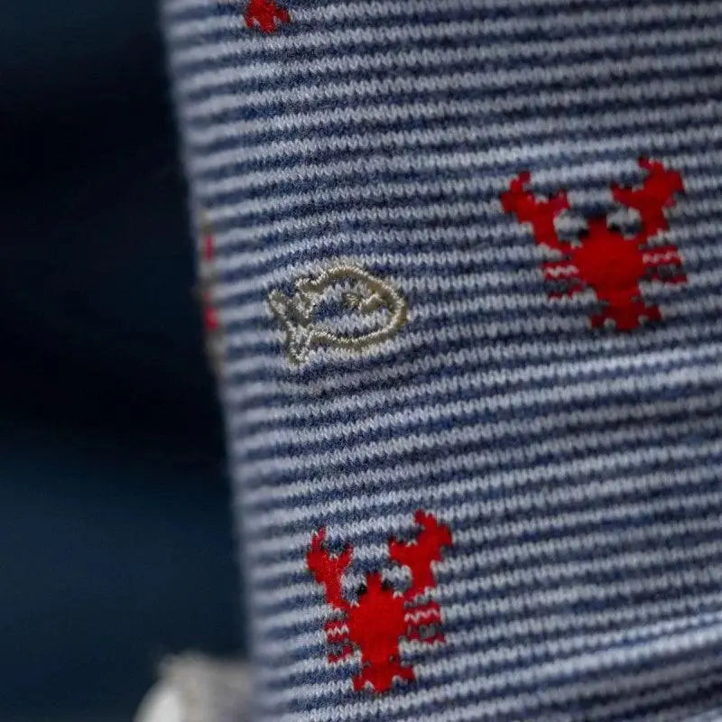 Gros plan sur les homards rouges et le logo poisson brodé des chaussettes BillyBelt rayées bleu et blanc