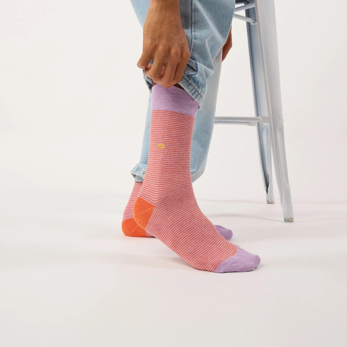 Chaussettes BillyBelt Crépuscule portées de profil avec un jean clair retroussé, talon orange et pointe lilas