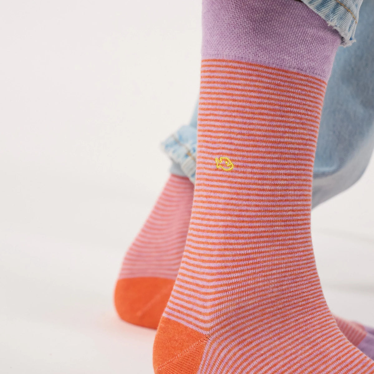 Gros plan sur les micro-rayures orange et violet clair et le logo BillyBelt brodé jaune des chaussettes Crépuscule