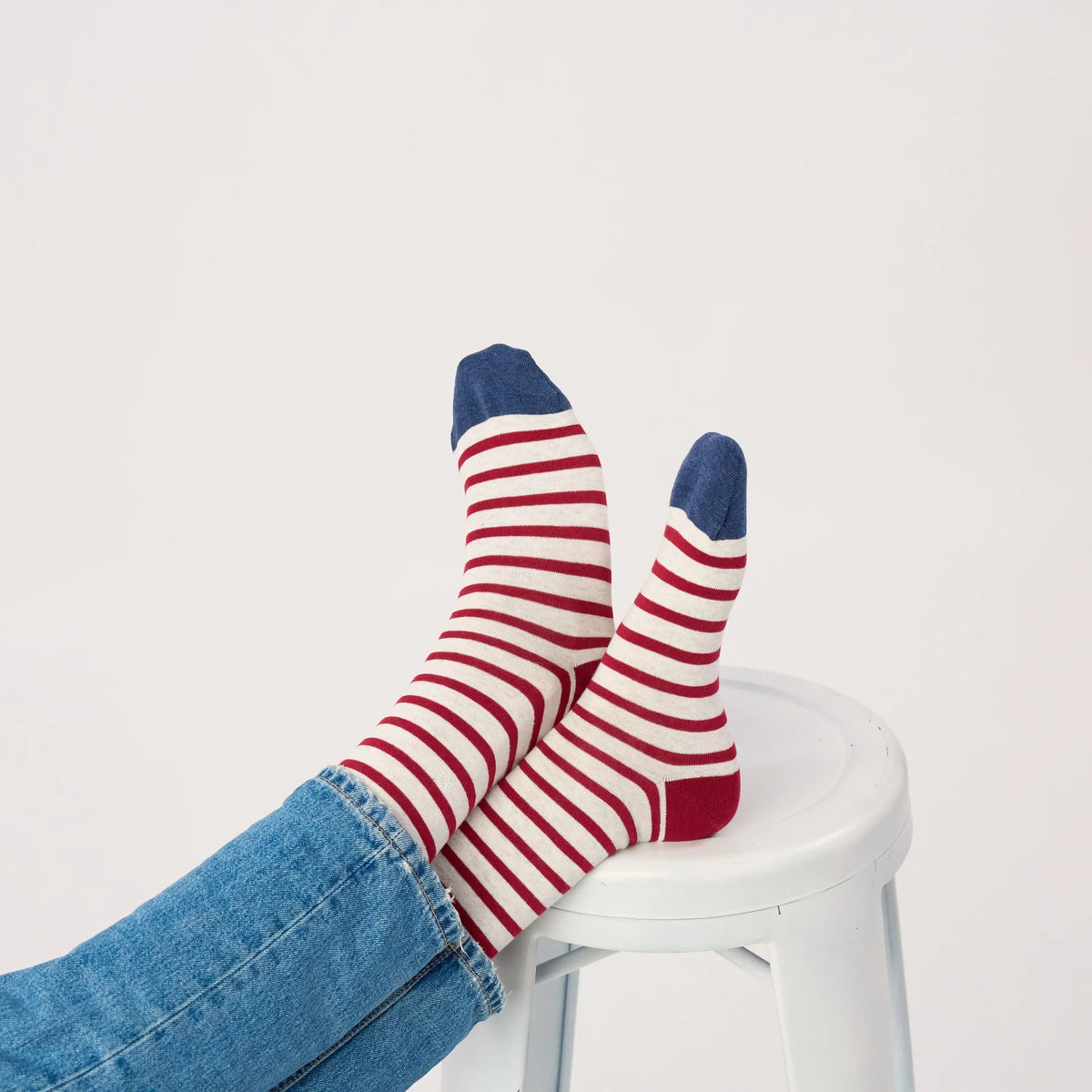Chaussettes BillyBelt Gris & Bordeaux portées, pieds croisés sur un tabouret blanc, pointes bleues
