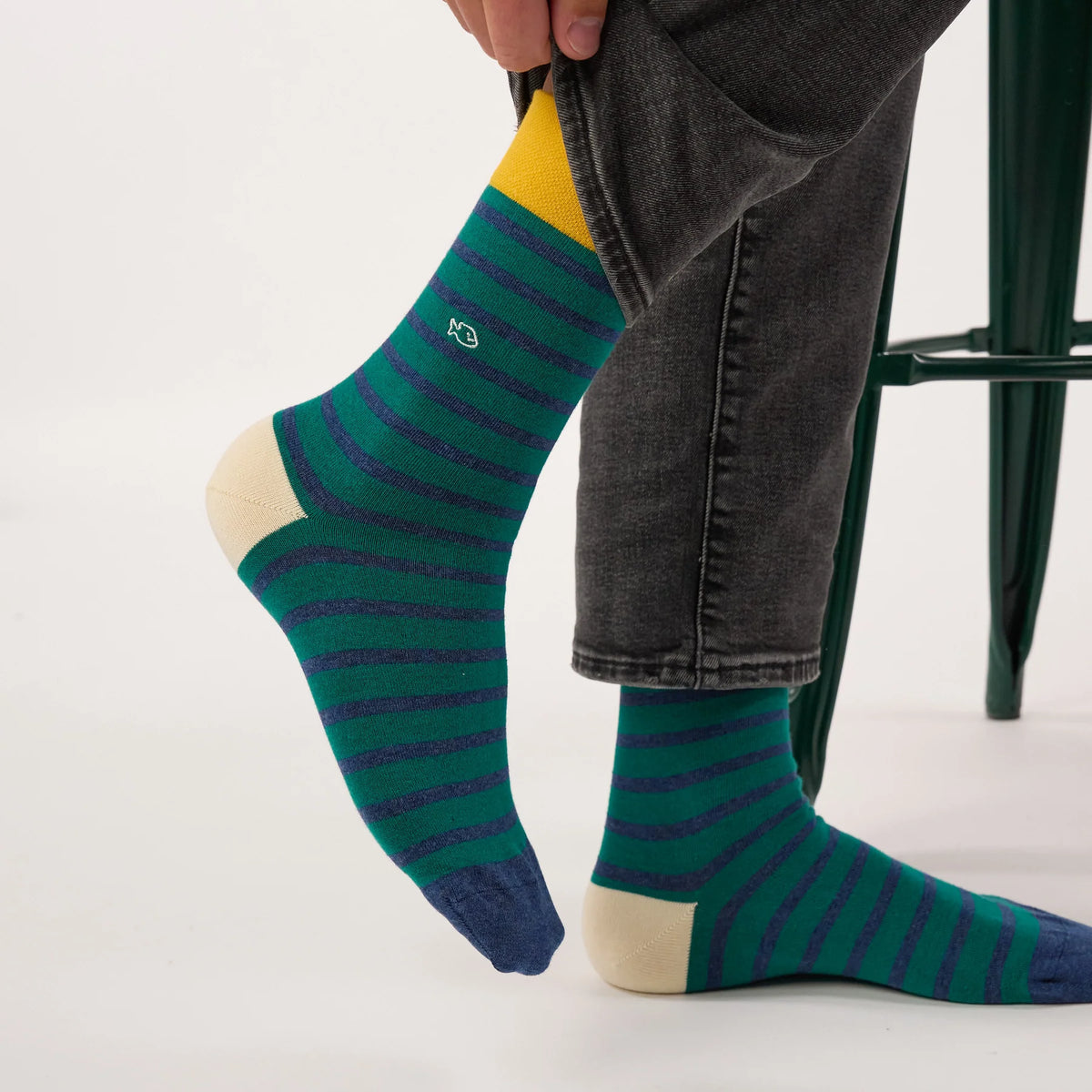 Chaussettes BillyBelt vertes à rayures bleues portées, jambe levée, vue sur le talon écru