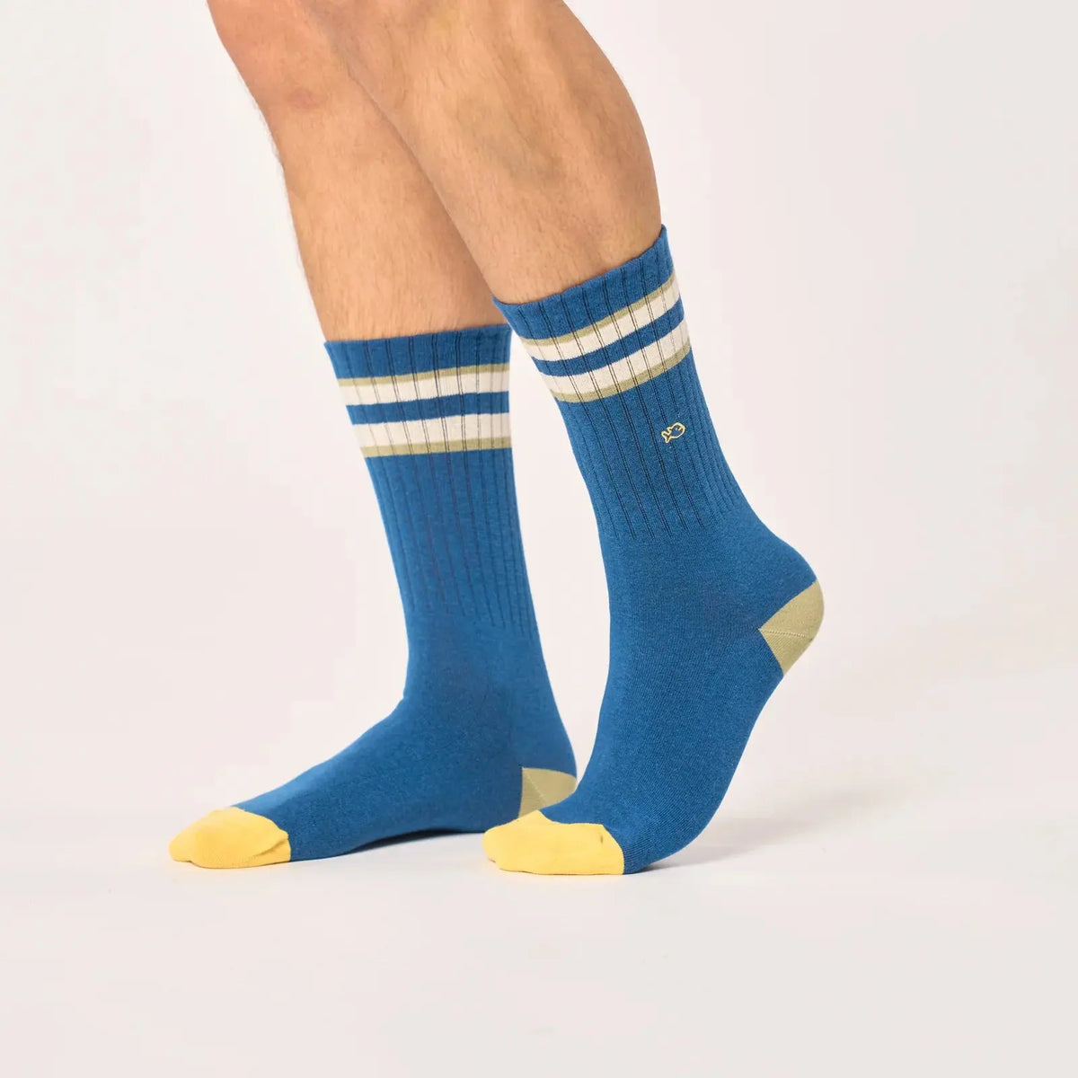 Paire bleu pétrole portée de face, bandes ivoire et kaki clair en haut de tige et pointes jaune vif.