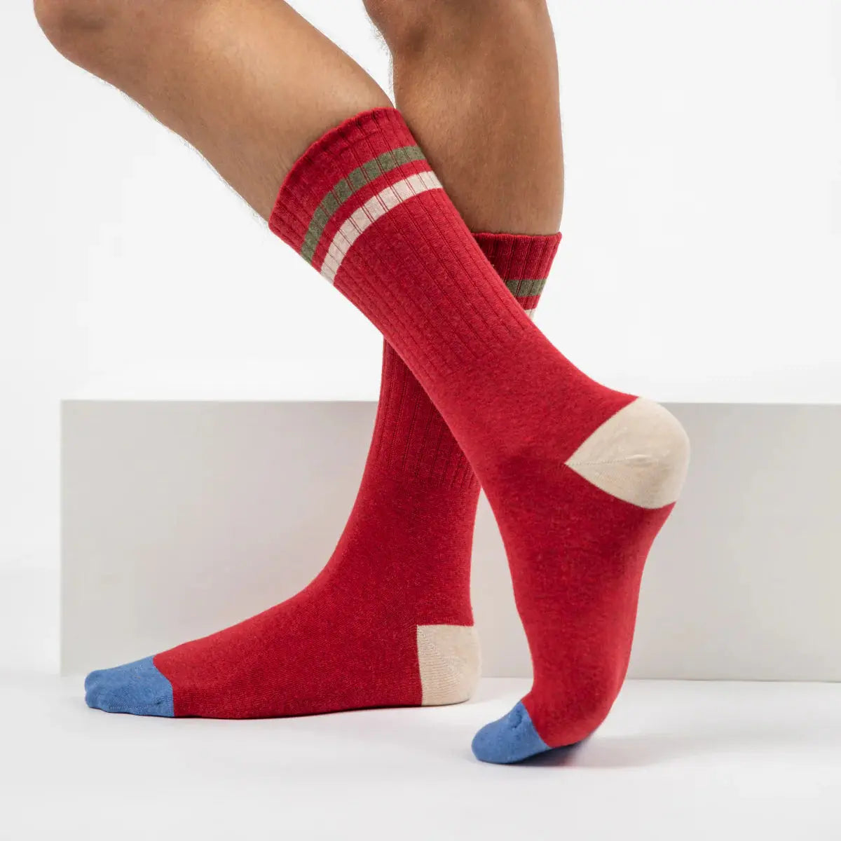 Chaussettes rouges vues de profil, talon écru et pointe bleu jean nets, bandes kaki et écrue en haut.