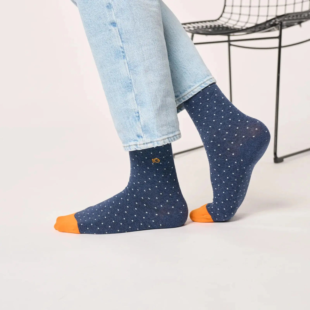 Chaussettes Bleu Marine chiné à micro-carrés blancs vues de trois quarts, pointes orange vif au sol.