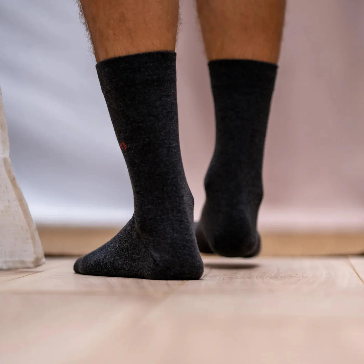 Chaussettes gris souris vues de dos, talons arrondis et tiges souples sur parquet
