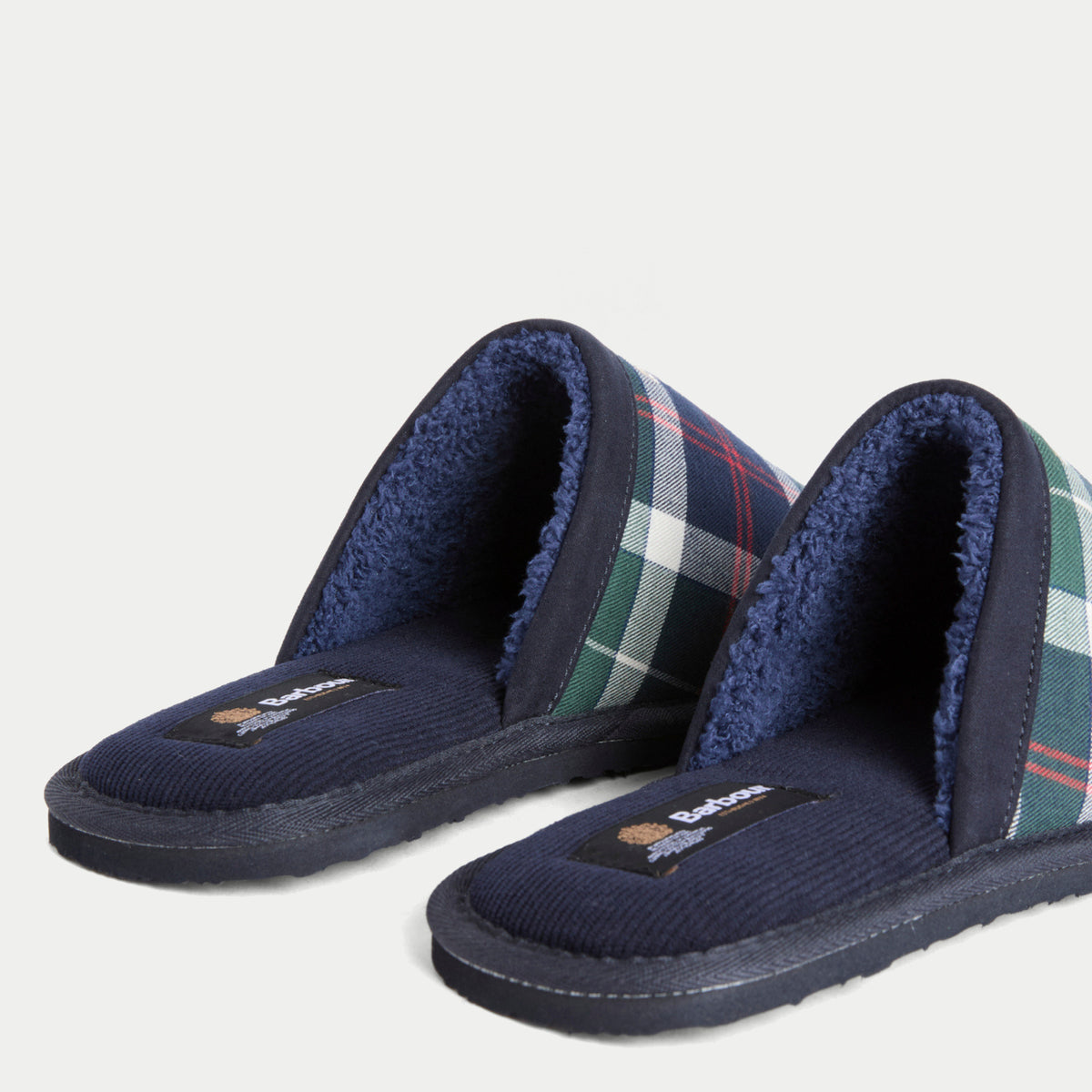 Détail des chaussons Everitt Tartan vert Barbour : première en velours côtelé marine, étiquette Barbour et doublure sherpa