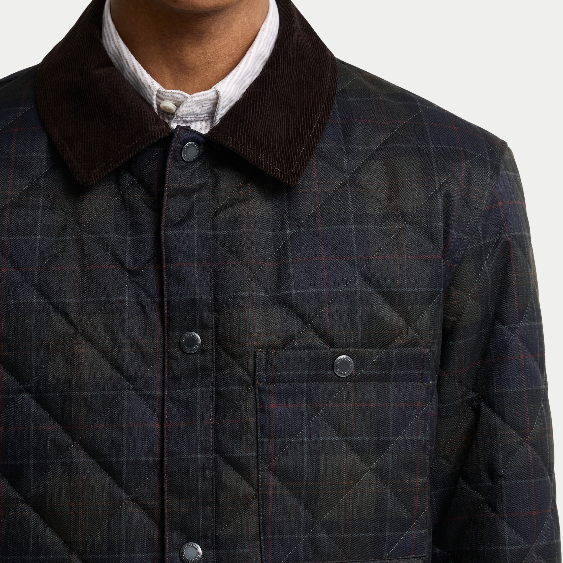 Gros plan du col en velours côtelé brun et de la poche poitrine à pression sur la veste-chemise Barbour tartan olive foncé