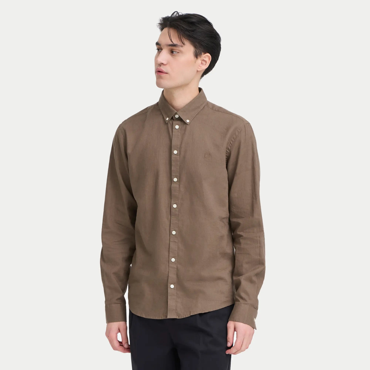Chemise en lin marron portée sur un pantalon noir, tombé fluide et manches longues