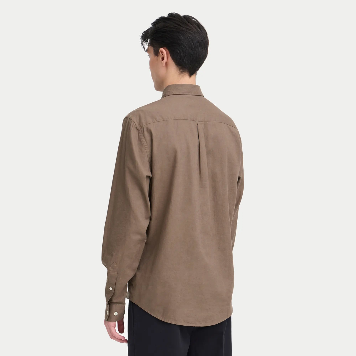 Vue de dos portée de la chemise marron, épaules aisées et poignets boutonnés