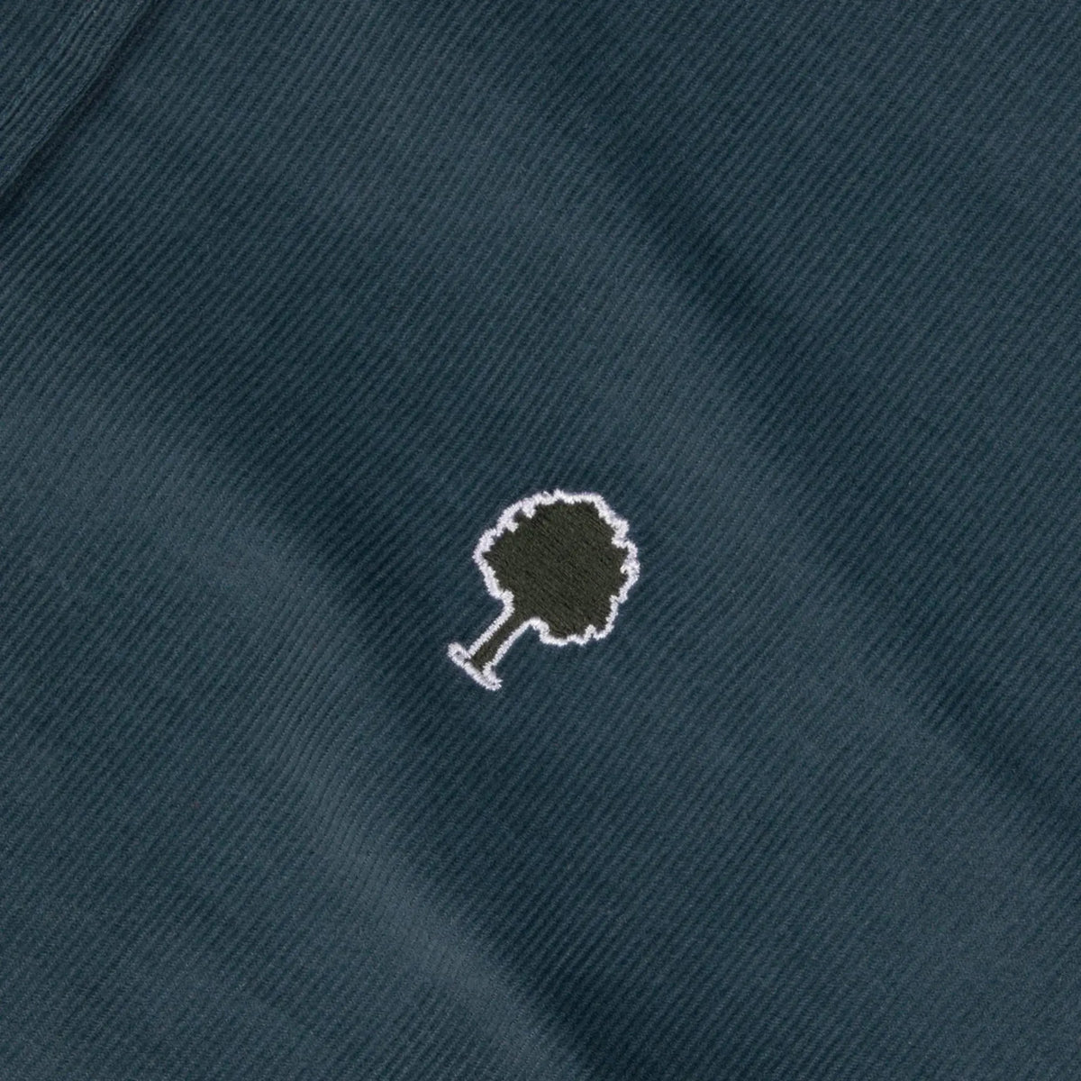 Détail du velours milleraies fin bleu pétrole de la chemise Ivoy Faguo et du logo arbre brodé kaki