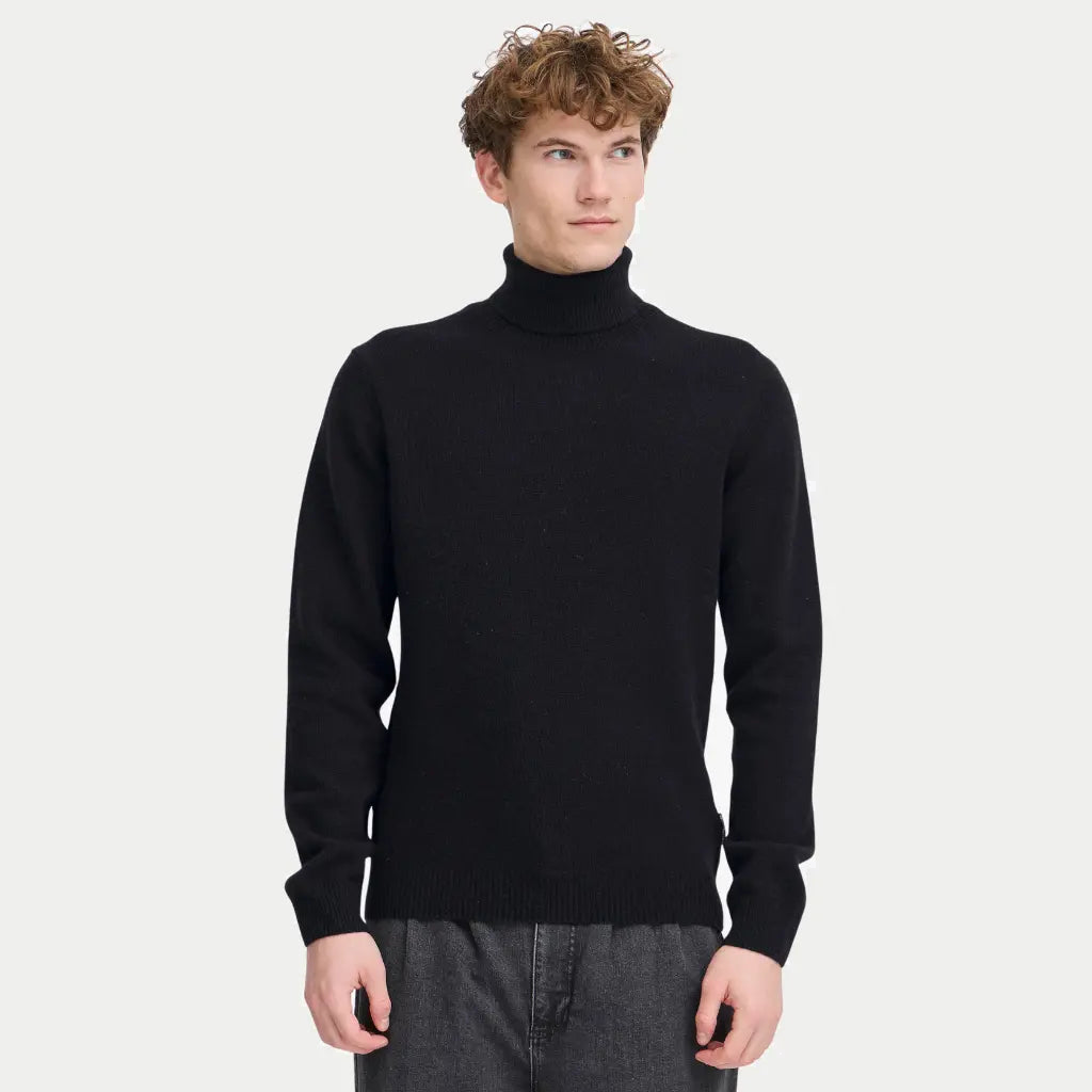 Col Roulé noir porté, maille mate et bord-côte de taille retombant sur un jean gris