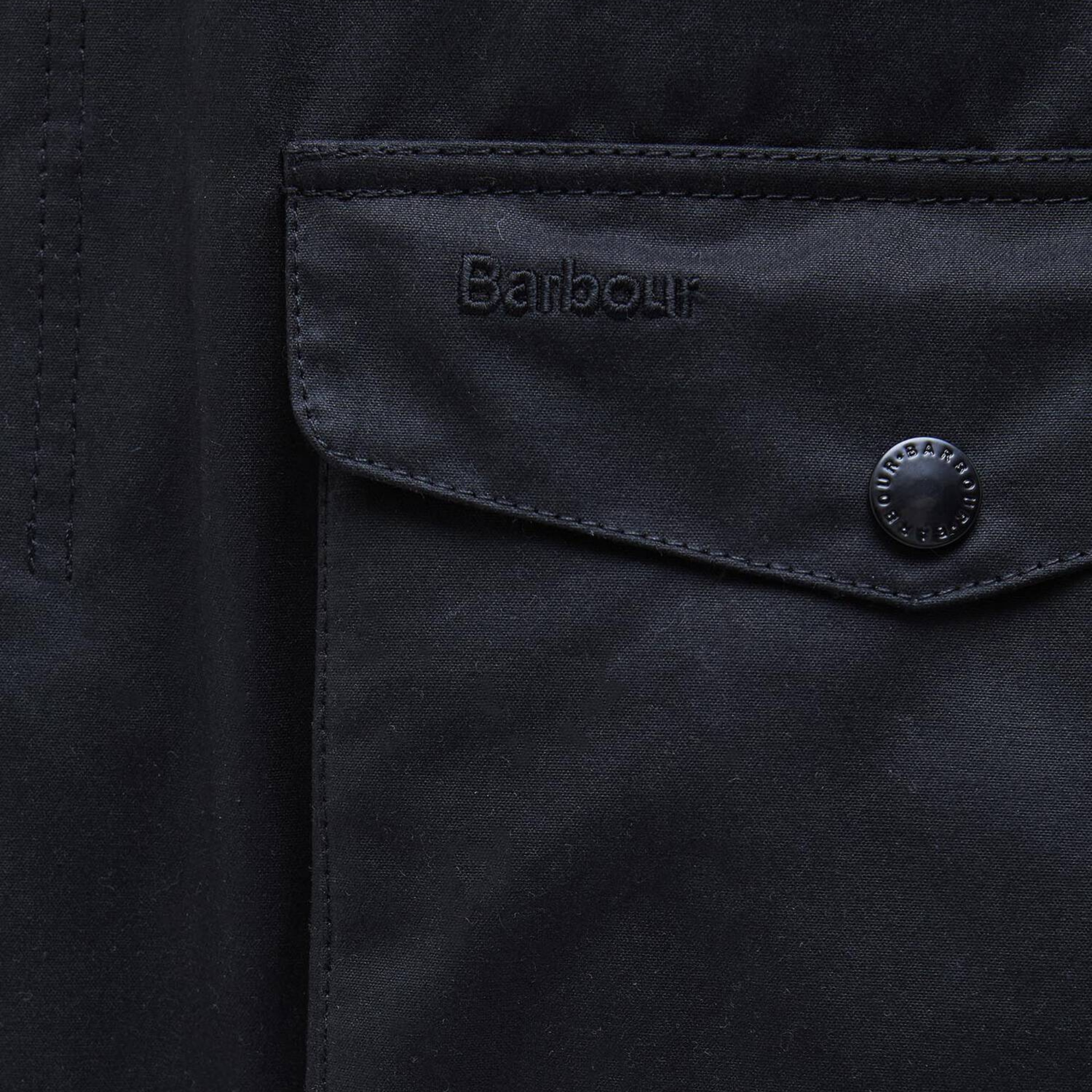 Rabat de poche basse de la veste cirée Ogston Barbour marine : broderie ton sur ton et pression gravée