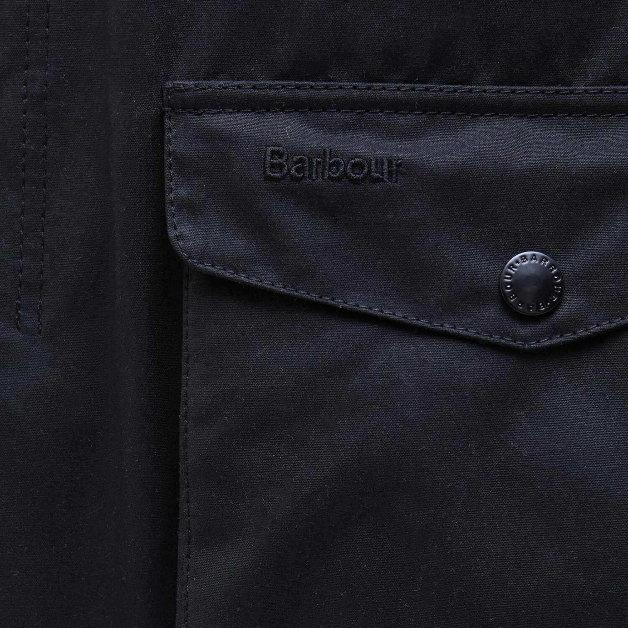 Rabat de poche basse de la veste cirée Ogston Barbour marine : broderie ton sur ton et pression gravée