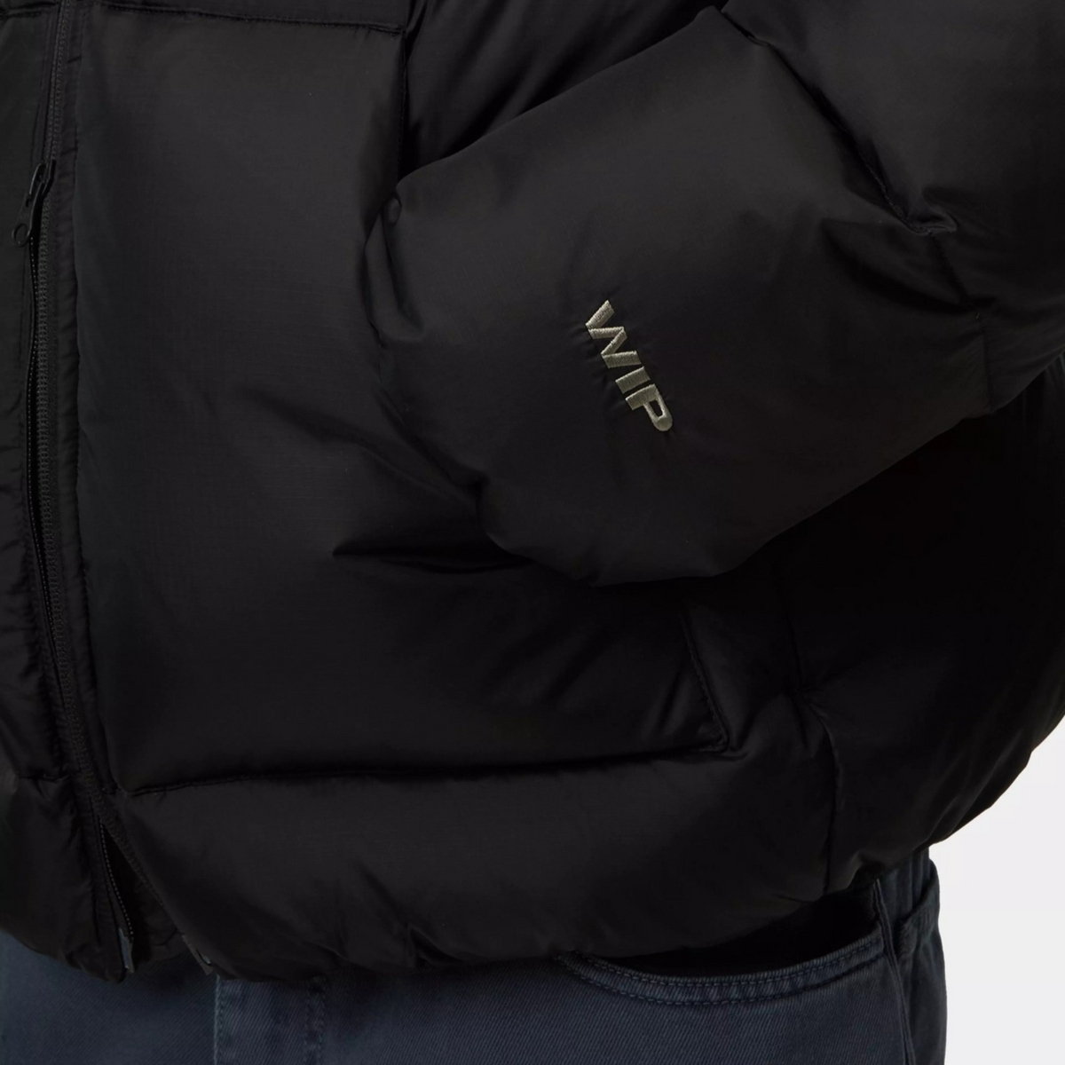 Détail de la doudoune Carhartt WIP Ardon noire : logo WIP brodé gris sur la manche en ripstop