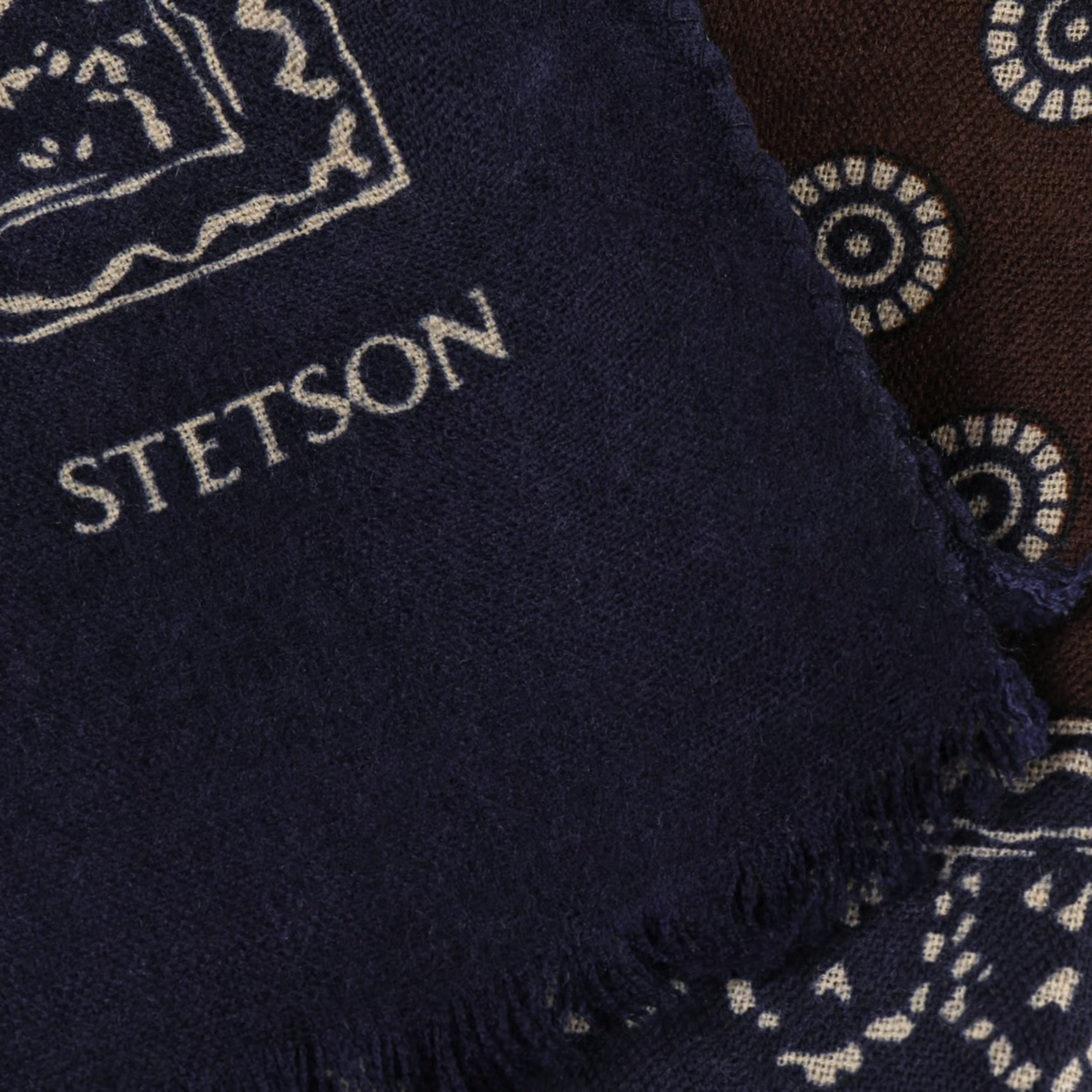 Coin bleu marine de l'écharpe à pois : lettrage Stetson écru, bord effrangé et rosaces du centre marron