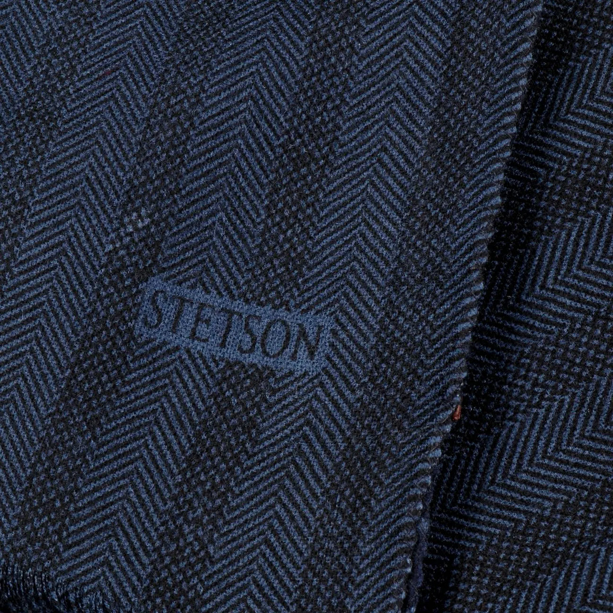 Gros plan du tissage à chevrons bleu marine et noir de l'écharpe Stetson chevrons à pois, logo de la marque ton sur ton