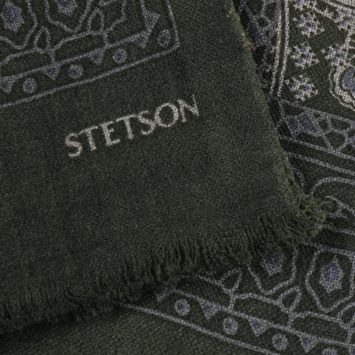 Coin de l'écharpe à imprimé paisley vert foncé : lettrage Stetson gris clair, bord effrangé et frise géométrique