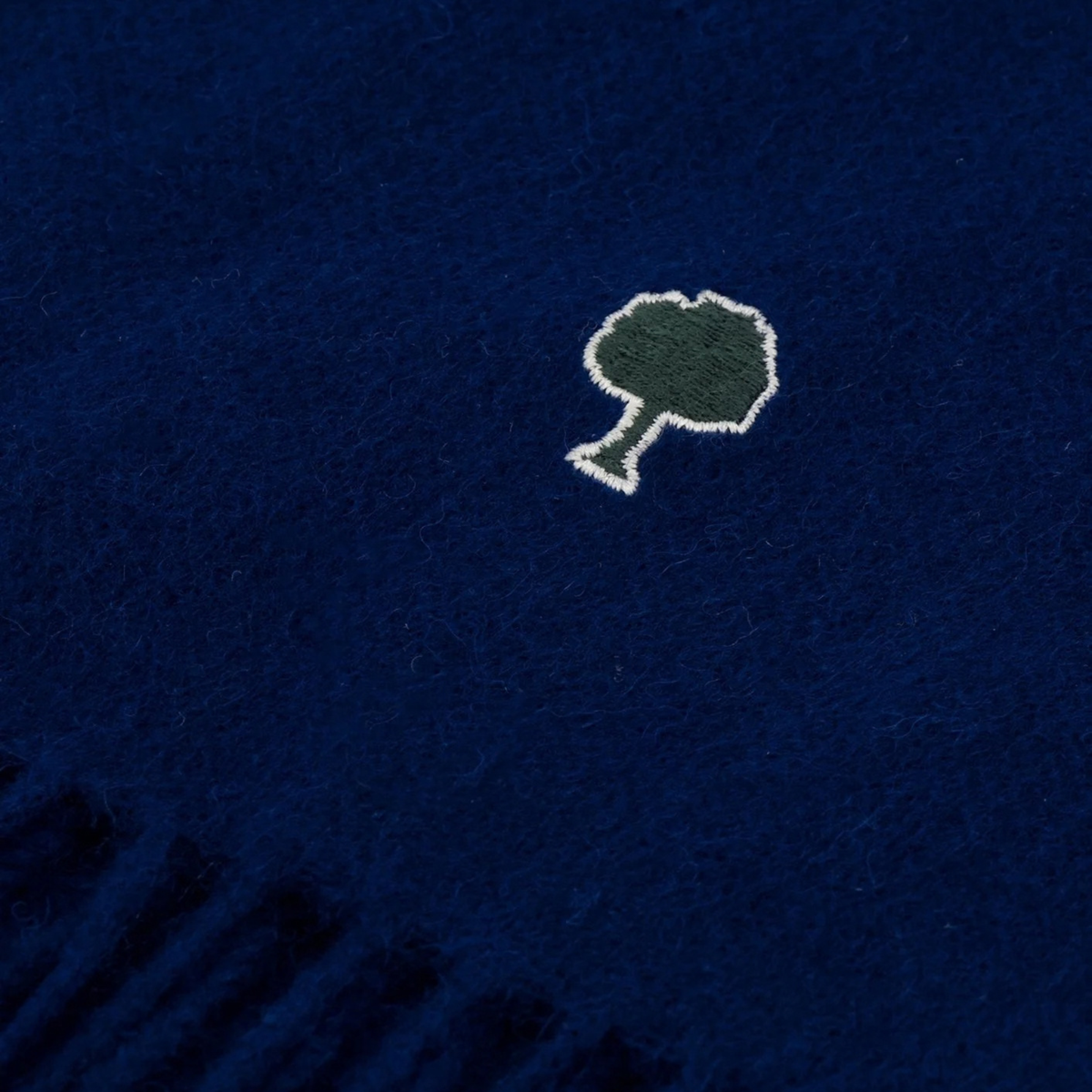 Zoom sur la laine grattée bleu marine et l'arbre Faguo brodé vert sapin cerclé d'écru