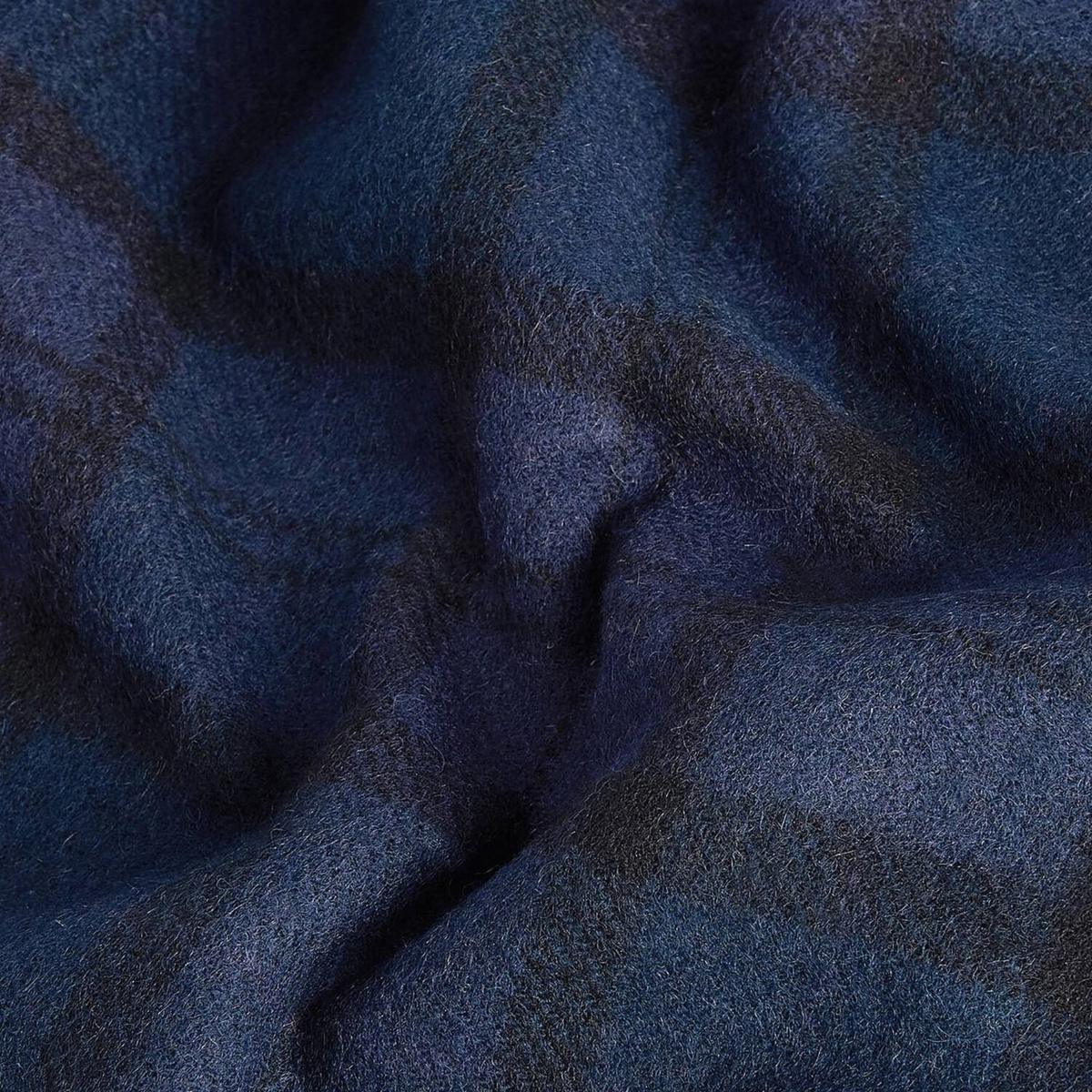 Gros plan sur la laine d'agneau de l'écharpe Barbour, tartan bleu marine et vert sapin drapé