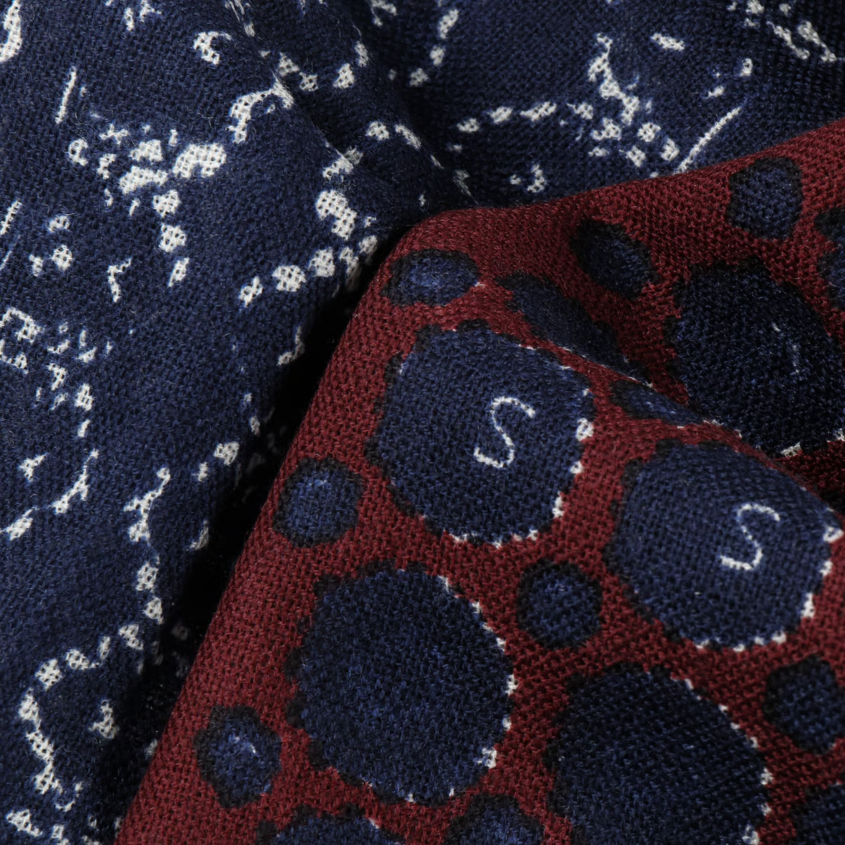 Détail de l'écharpe Ornaments Stetson : ornements blancs sur bleu marine et revers bordeaux à pois siglés S