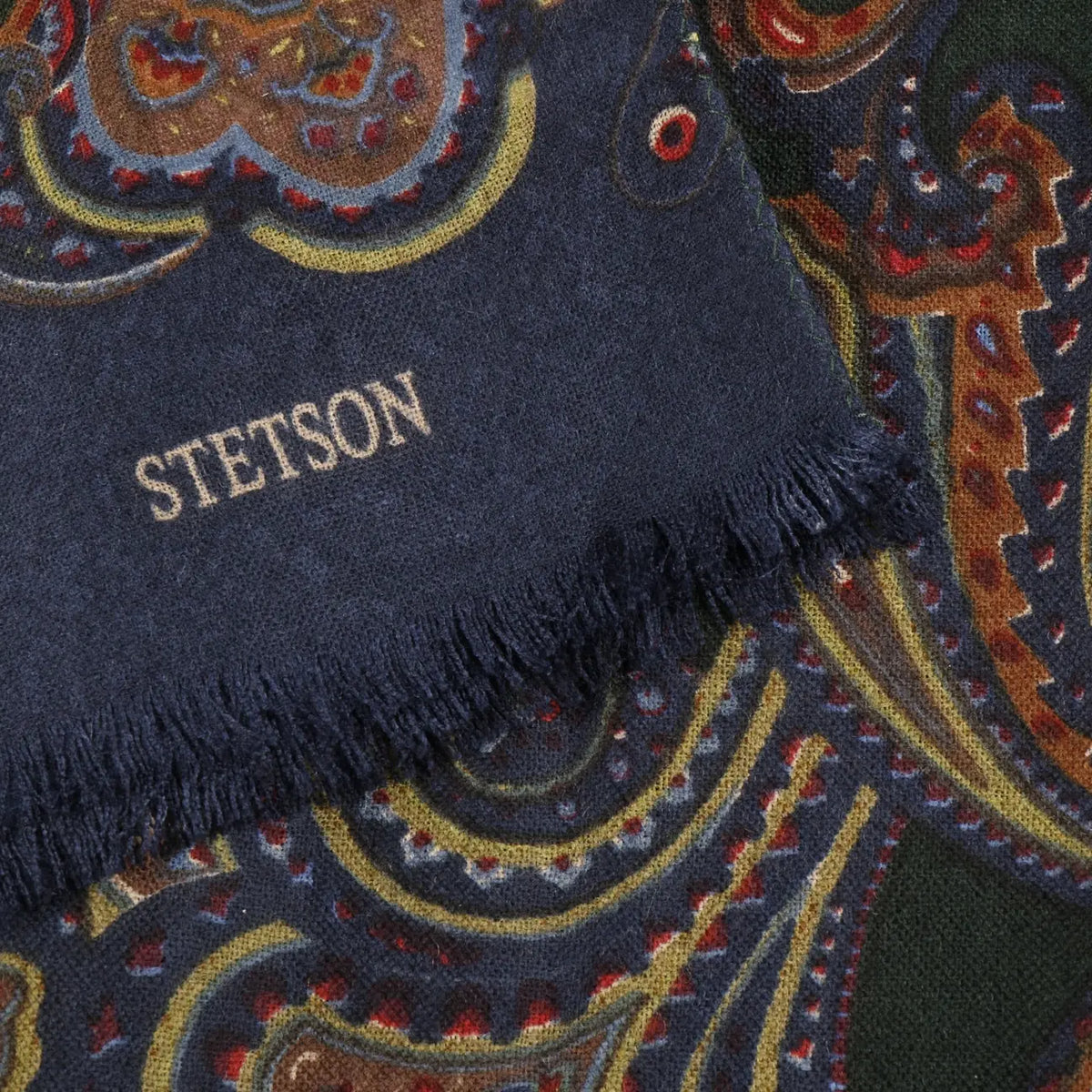 Détail du bout bleu marine de l'écharpe Paisley Stetson : lettrage Stetson et franges courtes sur le motif paisley