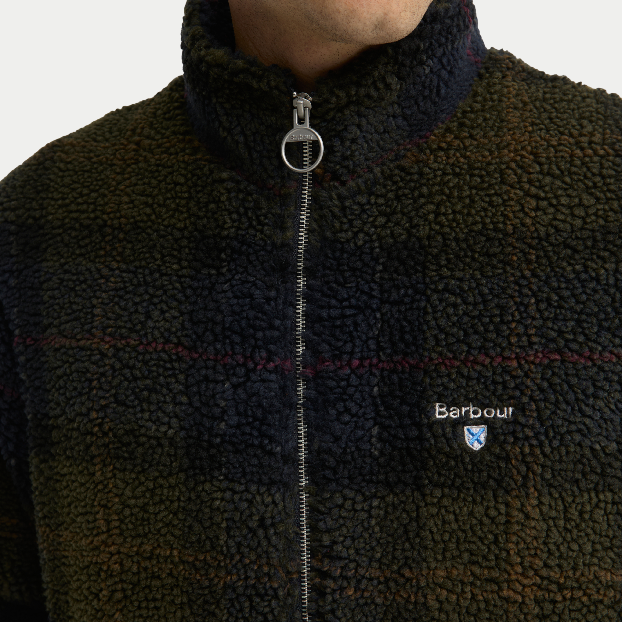 Détail du sherpa bouclé tartan olive foncé, filets rouges et tirette anneau métal Barbour