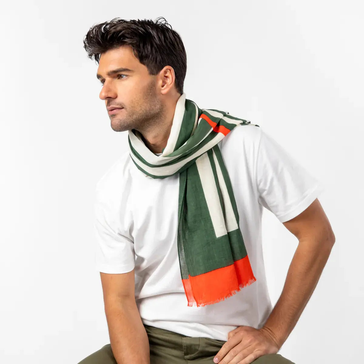Foulard à larges rayures vert kaki et écru noué au cou, pan bordé d'orange retombant devant le buste