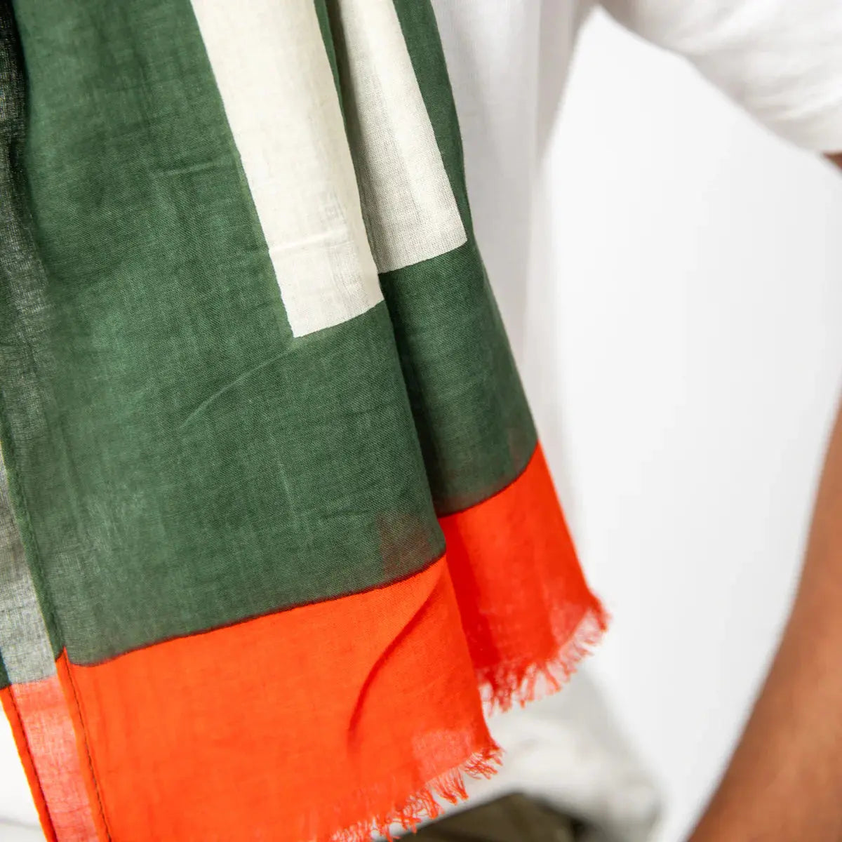 Extrémité du foulard : aplat vert kaki, large bordure orange vif et franges effilochées en bout de pan