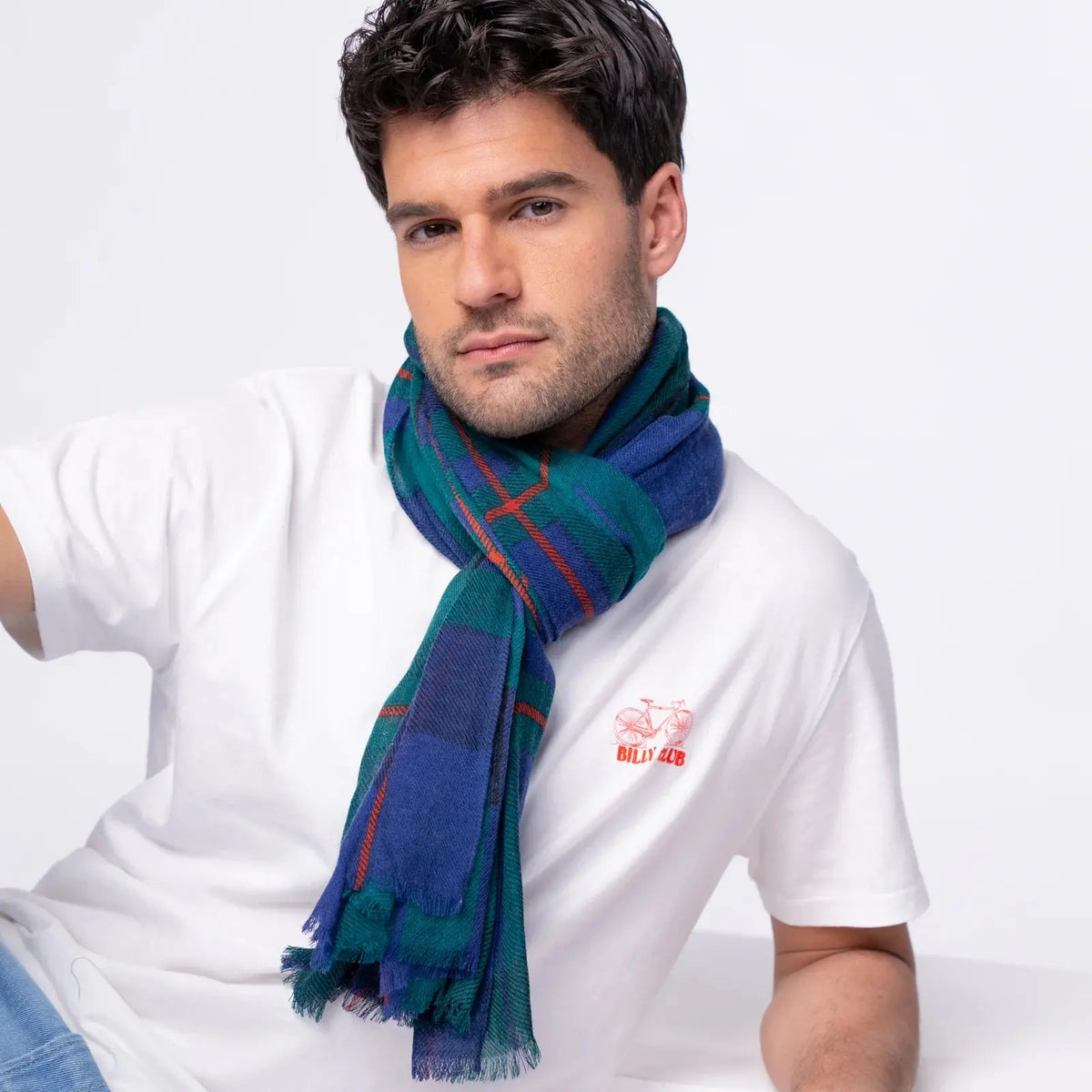Foulard à carreaux vert sapin et bleu roi porté en écharpe, franges au bout des deux pans libres
