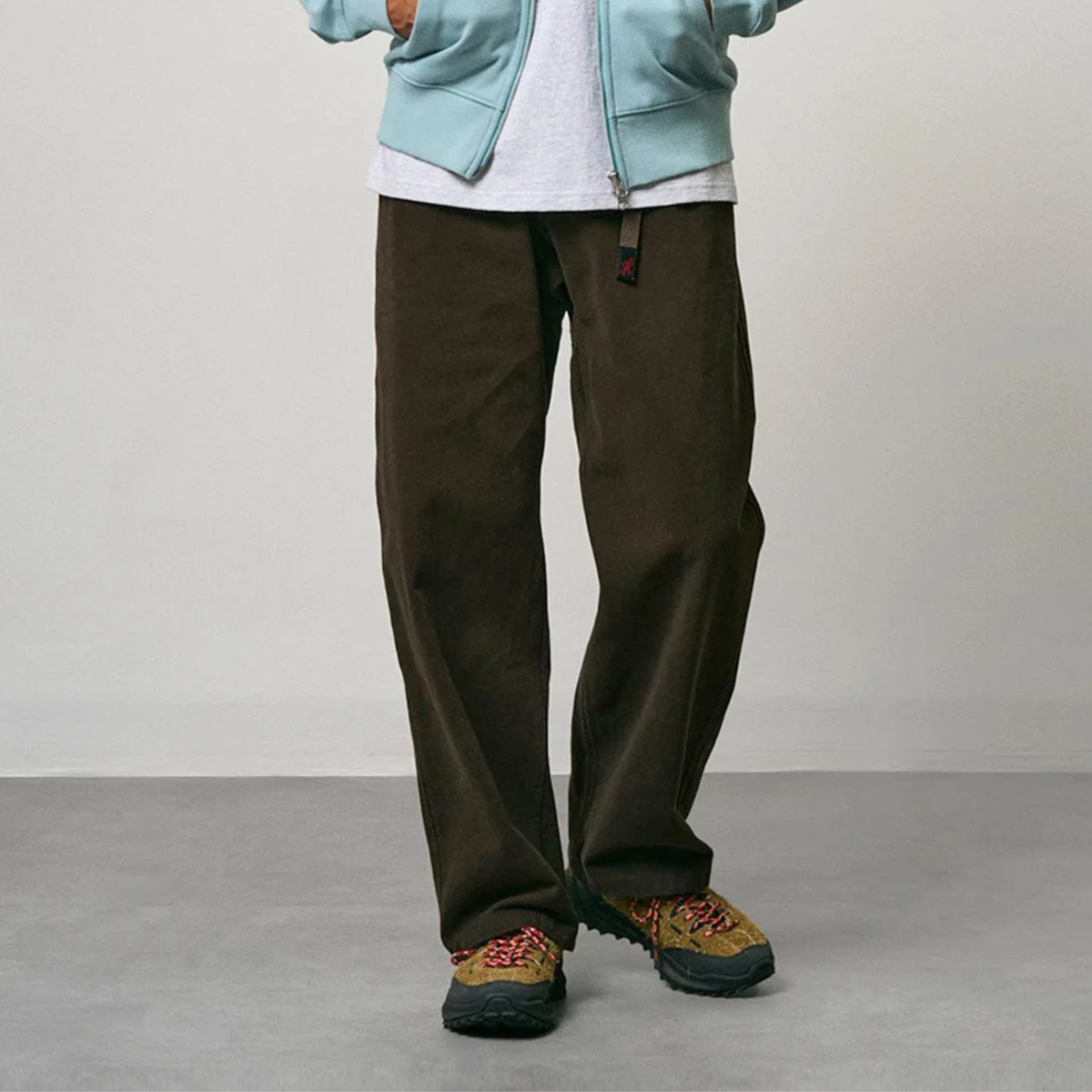 Pantalon G-pant Winter Twill Gramicci brun café porté de face, coupe décontractée et jambe droite tombant sur la basket