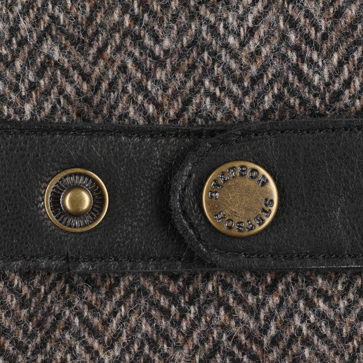Gros plan de la patte de cuir et du bouton-pression laiton gravé sur la laine