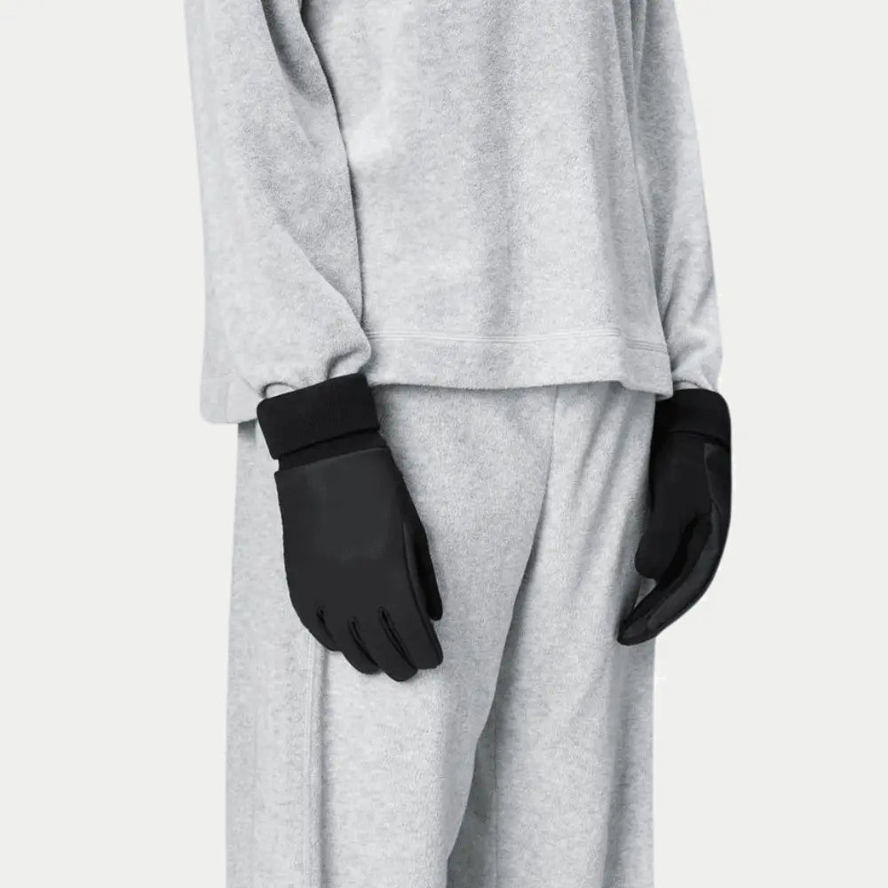 Les deux gants noirs portés le long du corps, paume enduite et bord-côte contrastant