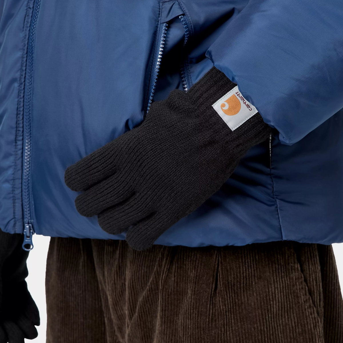Gants Watch Noir Carhartt WIP - porté, main gantée à la poche d'une doudoune bleue