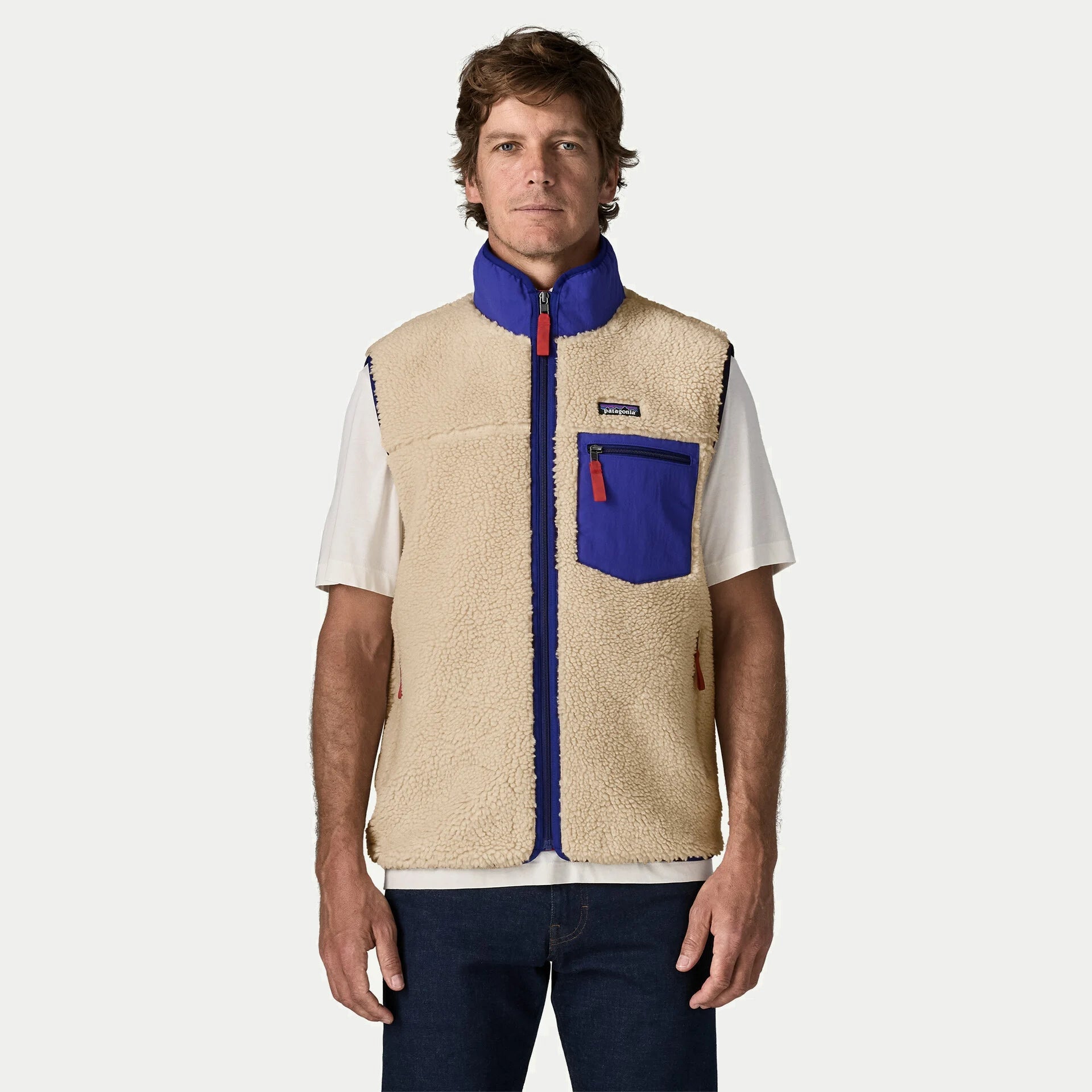 Gilet Retro-X Patagonia écru porté de face, col montant cobalt relevé et poche poitrine zippée sur t-shirt blanc
