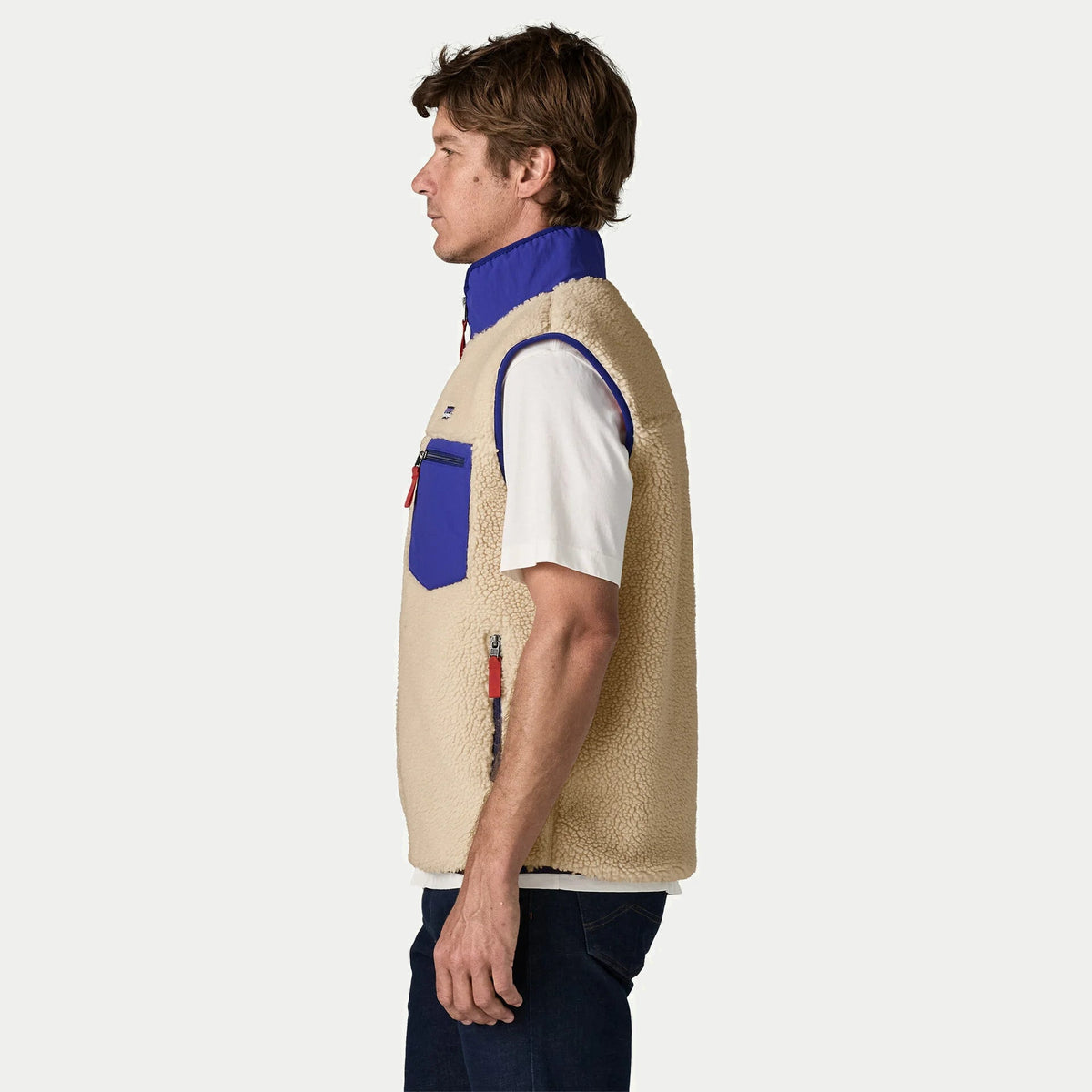 Gilet Retro-X Patagonia vu de profil : emmanchure bordée de cobalt et poche latérale zippée à tirette rouge