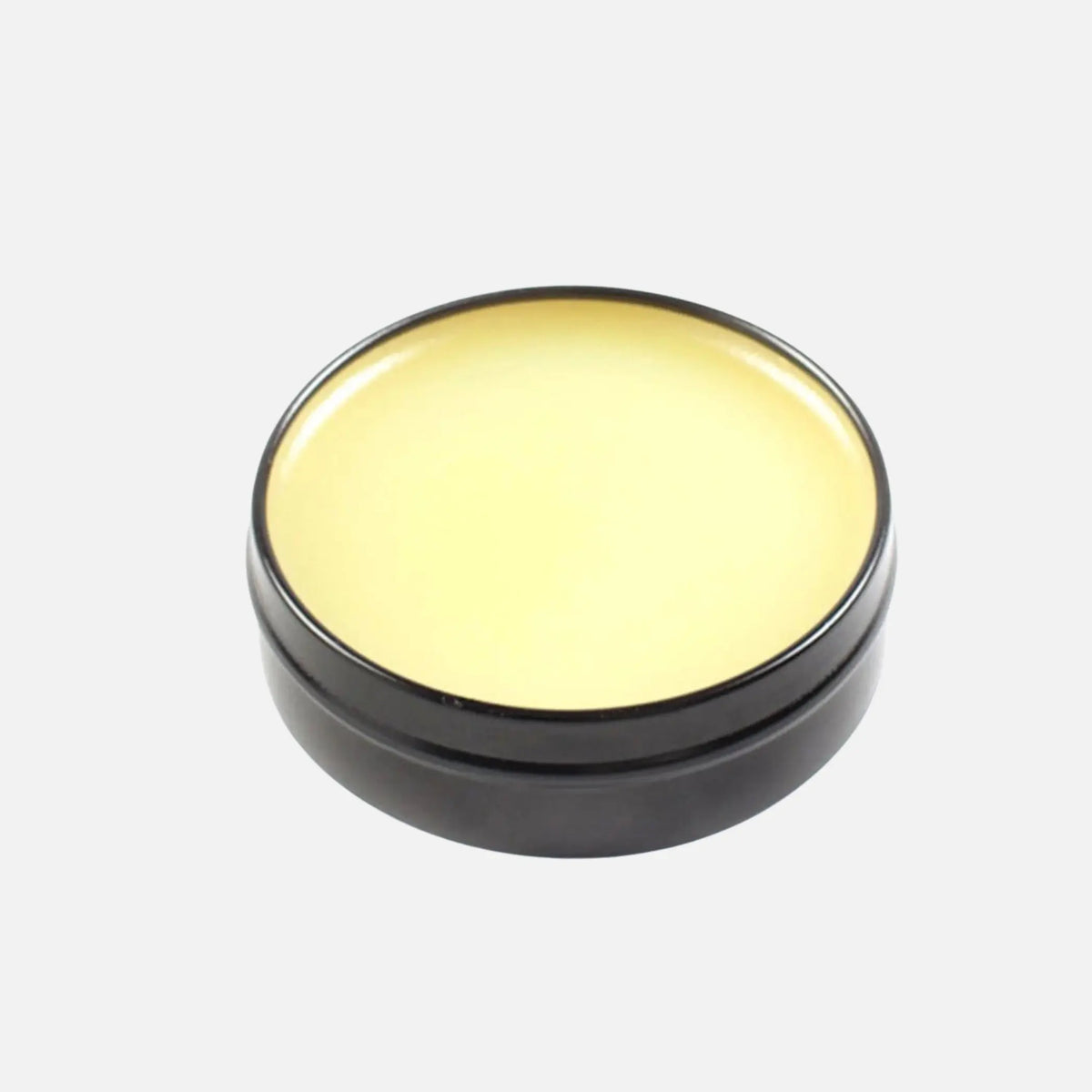Vue plongeante de la boîte ouverte : huile de vison jaune clair affleurant le bord métal noir