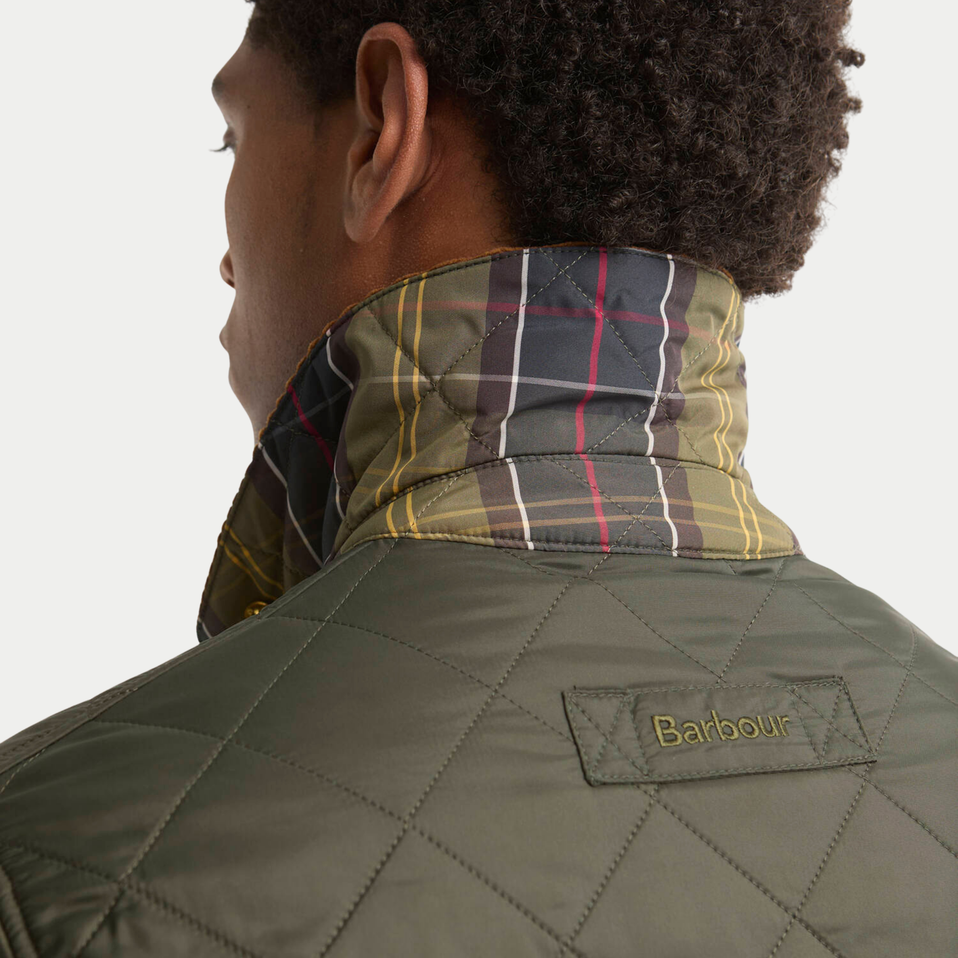 Col relevé de la veste Icons Heritage Liddesdale Barbour révélant la doublure tartan classique et le patch Barbour brodé