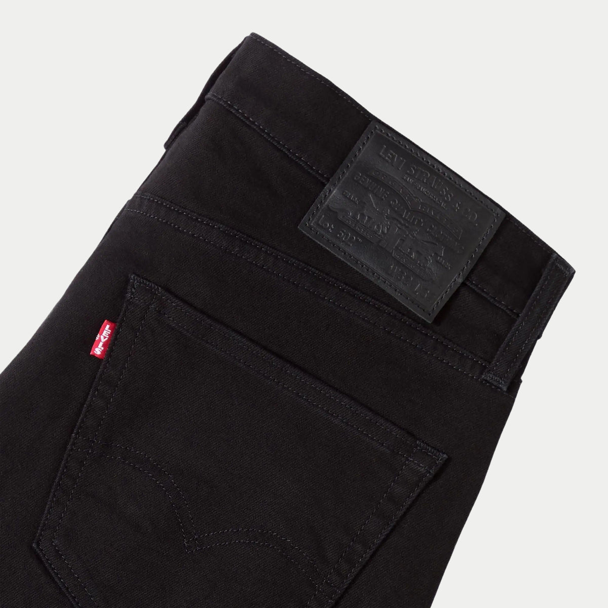 Détail dos du jean Levi's 502 Taper Sta-Dark Black : patch cuir gaufré Lot 502, red tab rouge et surpiqûre arcuate