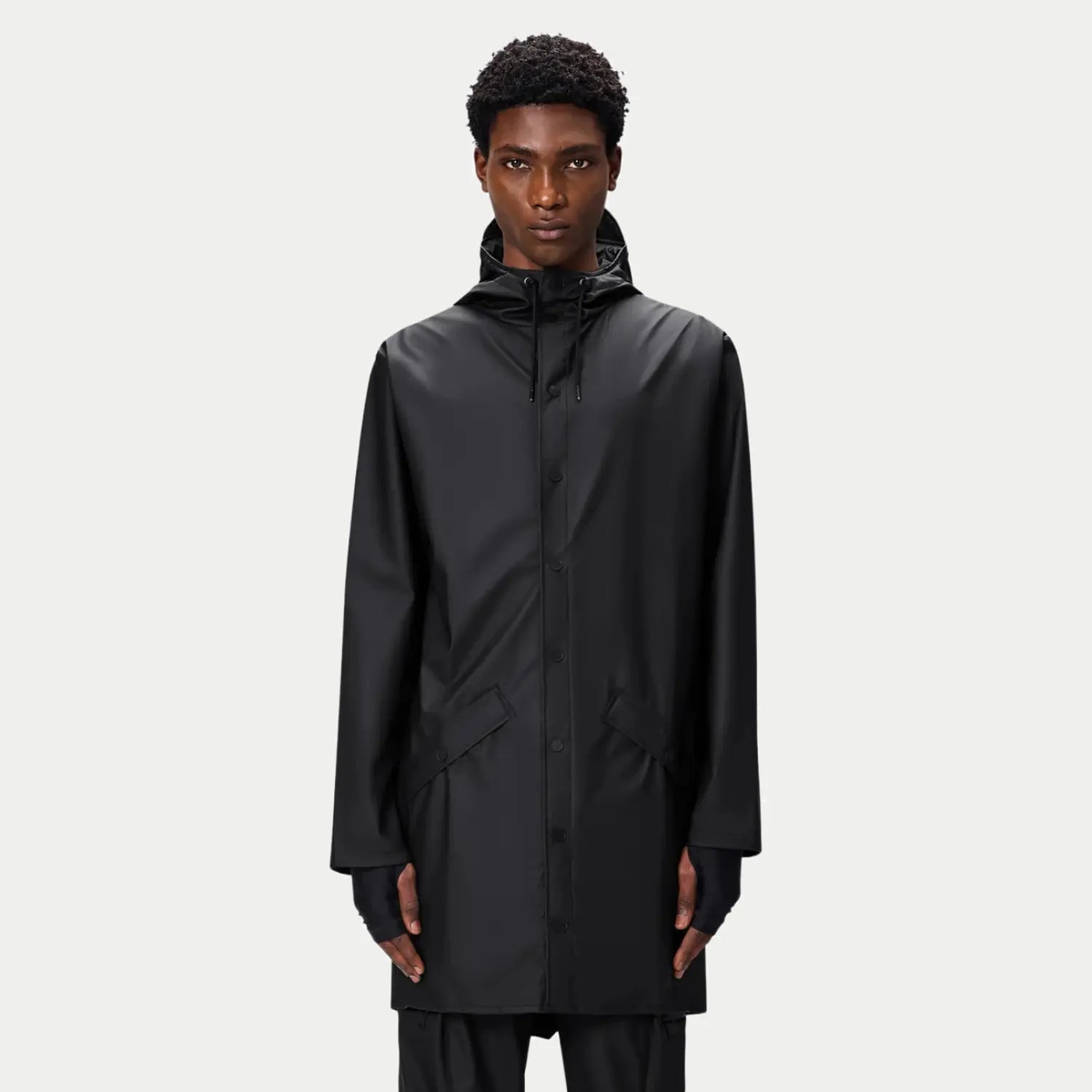 Long Jacket noire portée fermée, col haut cordé et longueur couvrant largement les hanches
