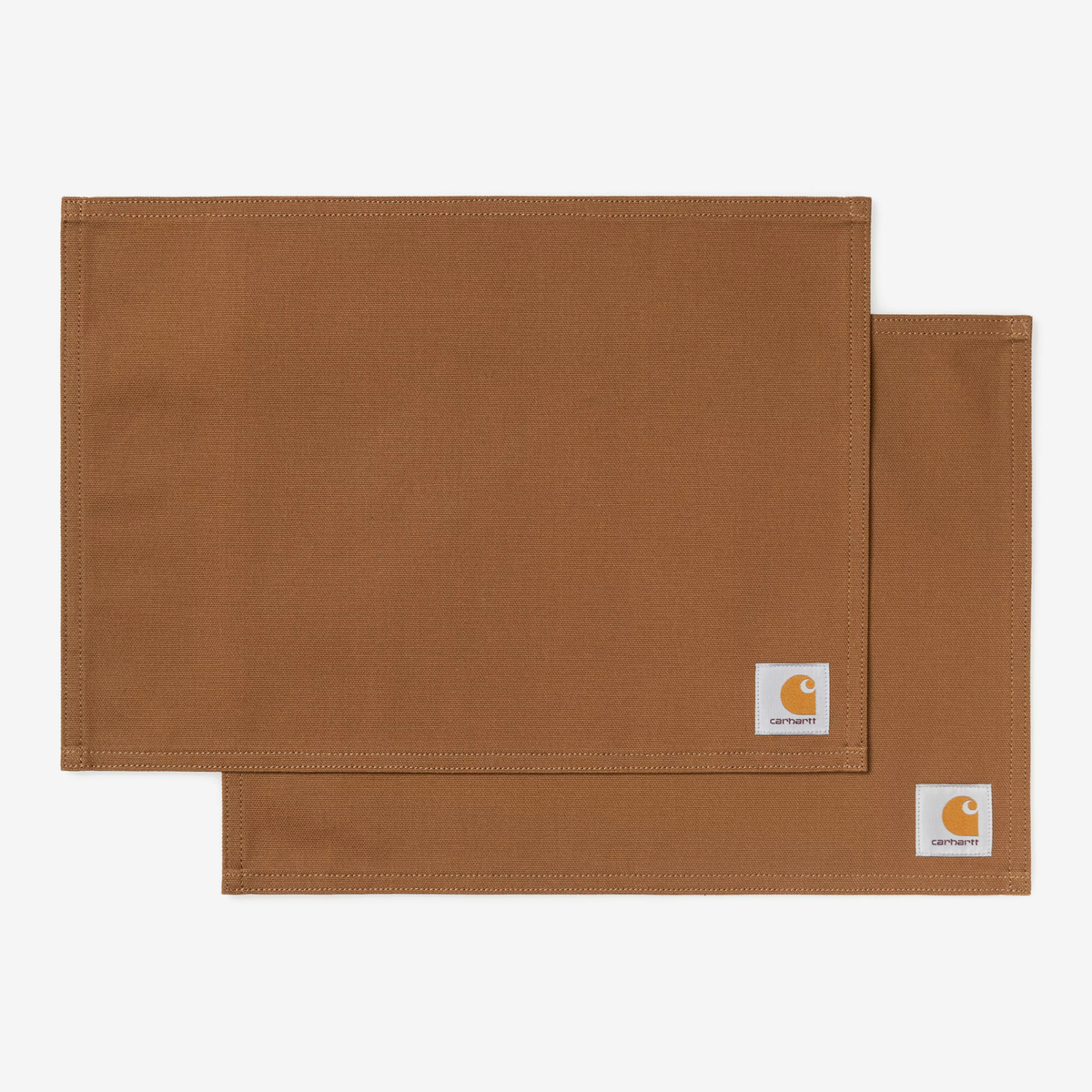 Les deux sets de table Canvas Carhartt WIP en toile Hamilton Brown, posés à plat superposés, Square Label tissé en angle.