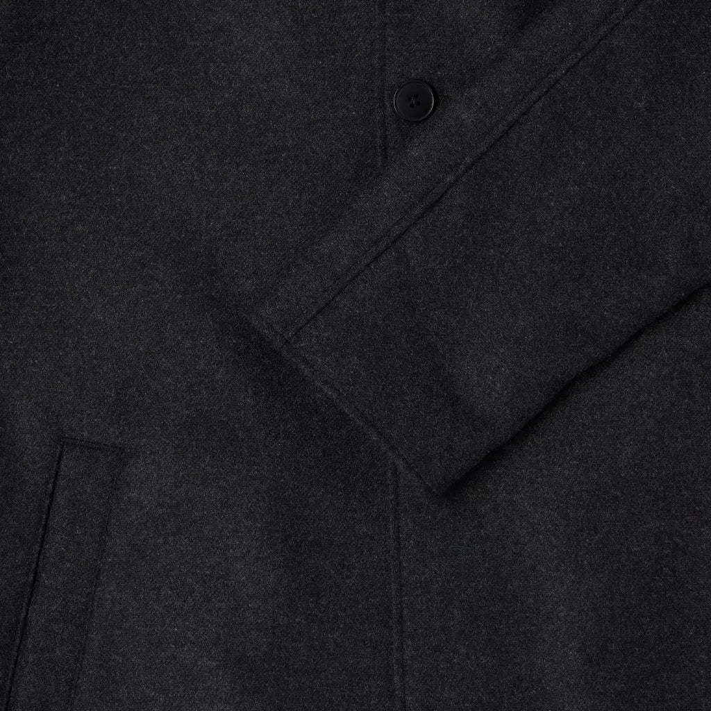 Bas de manche raglan du manteau Mac en laine gris anthracite, bouton noir et poche passepoilée
