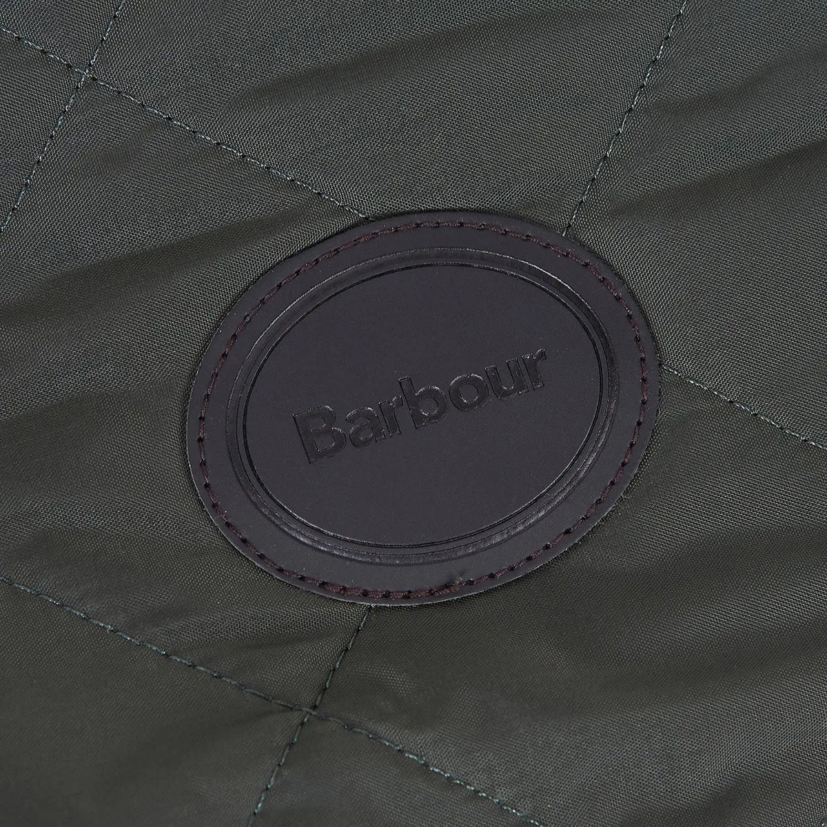 Macro du patch cuir ovale Barbour cousu sur le matelassage losange vert olive
