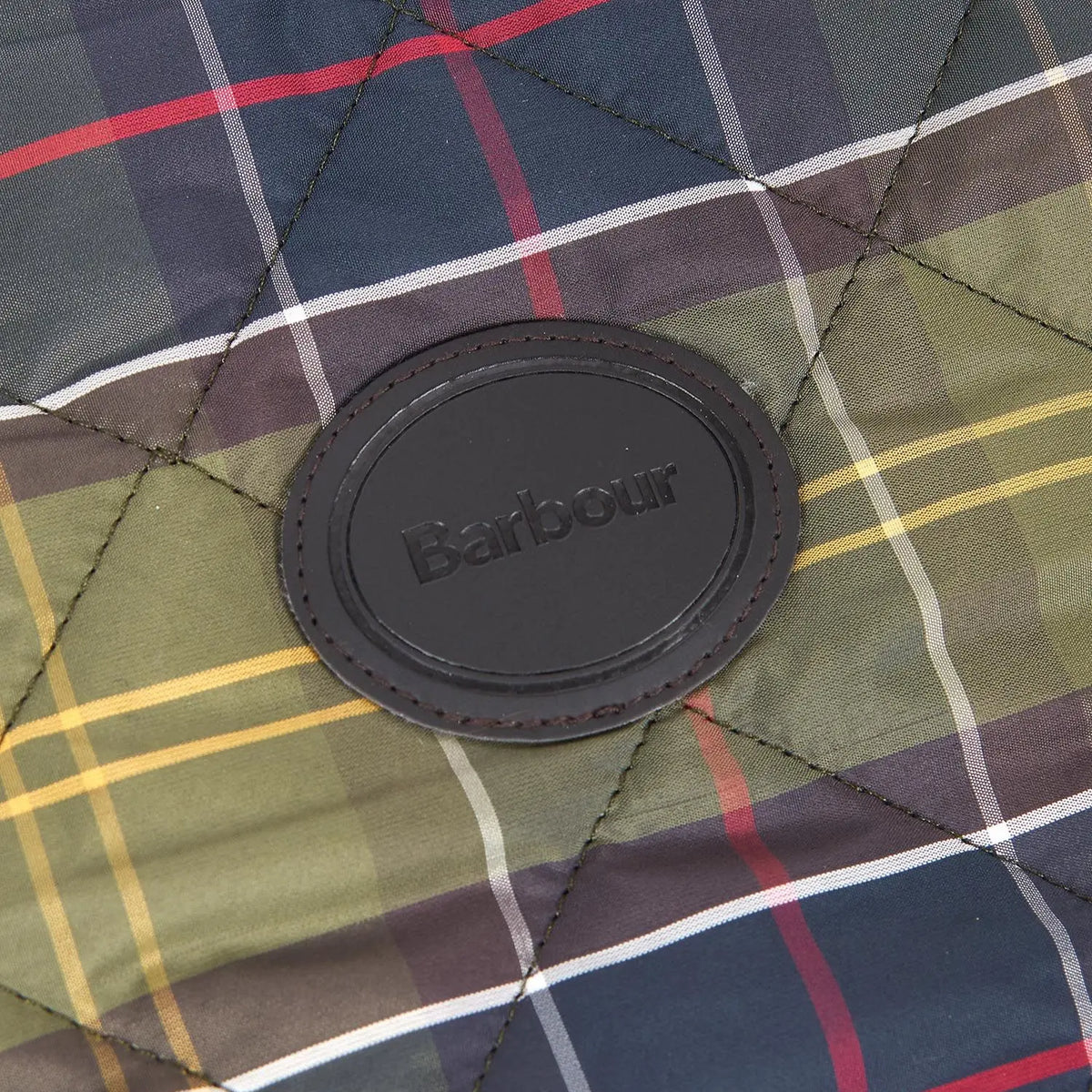 Macro du tartan matelassé olive, bleu nuit, rouge et jaune et du patch cuir Barbour