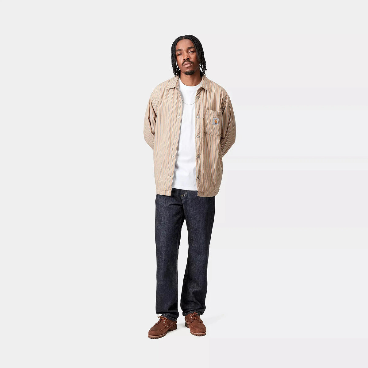 Silhouette complète en Marlow Pant Blue Rinsed, jean droit indigo brut porté sous une surchemise rayée beige