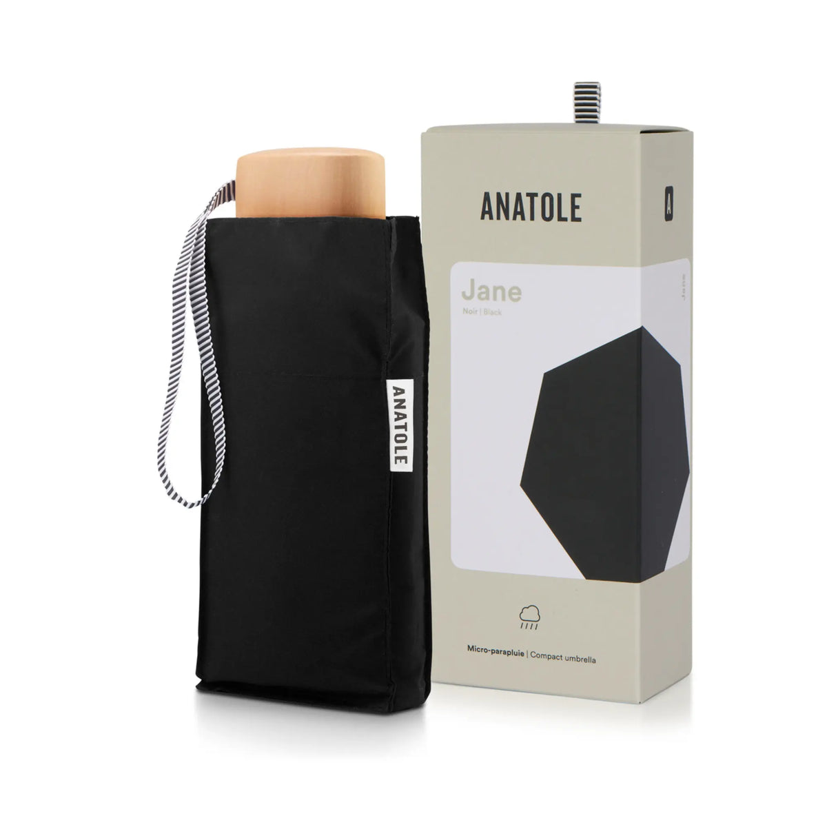 Mini parapluie Jane noir glissé dans sa housse, poignée en bois clair et dragonne rayée, coffret Anatole derrière